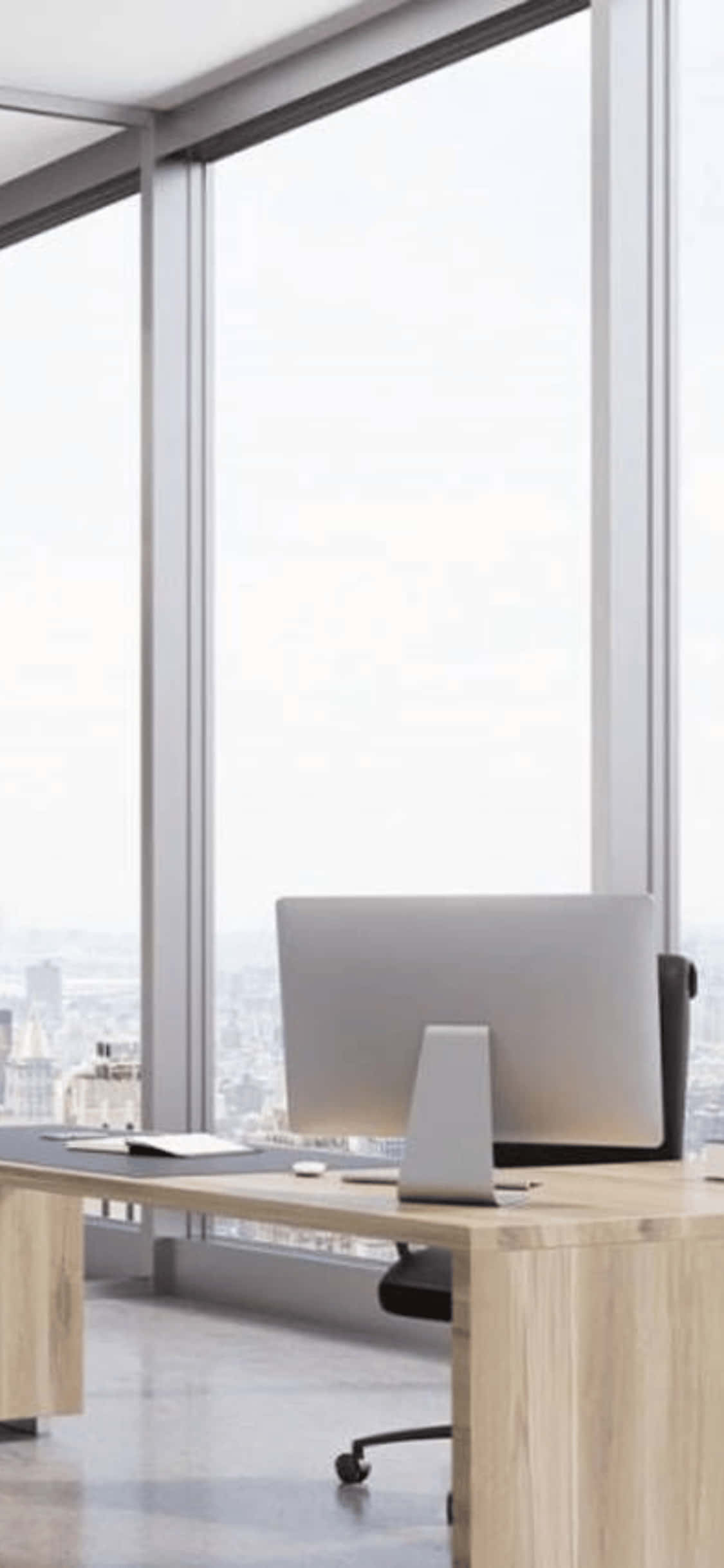 iPhone X Office 桌布 壁紙 — 現代簡約辦公桌，配備時尚電腦，透過落地窗可欣賞城市景觀。
