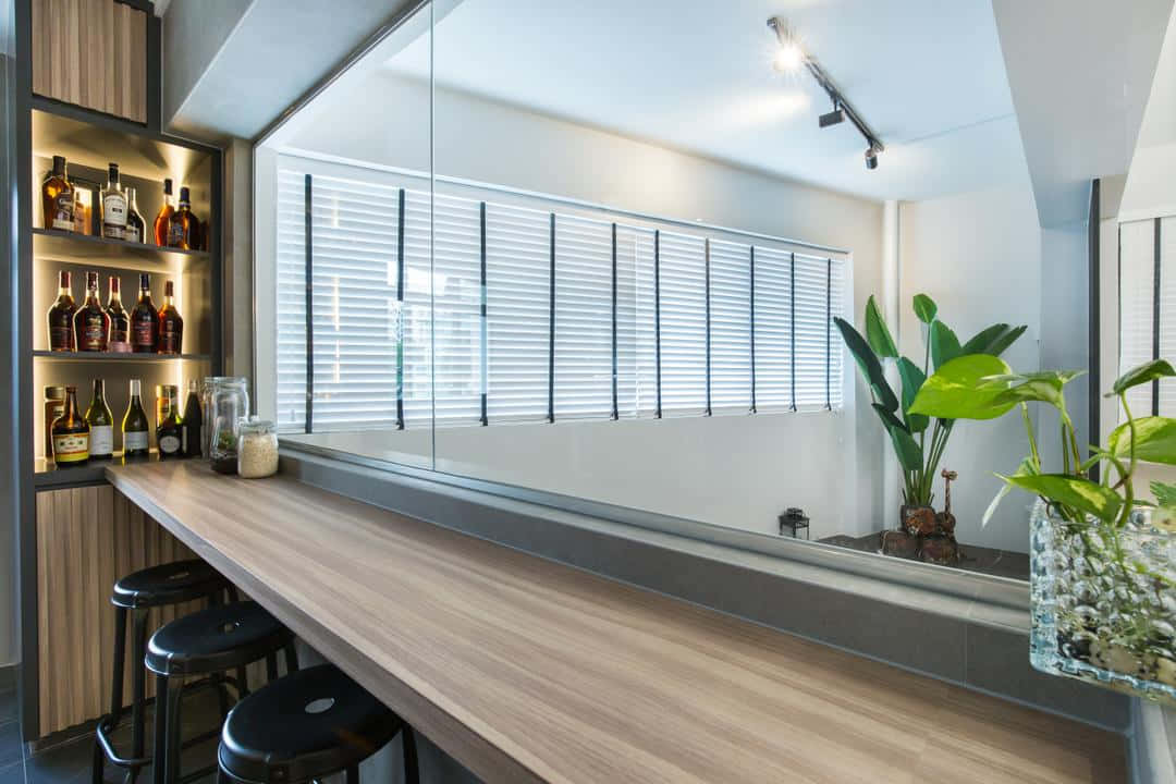 Bar 桌布 壁紙 — 現代簡約風格酒吧，配有木質吧檯、黑色高腳凳和酒瓶架，在溫暖燈光下。