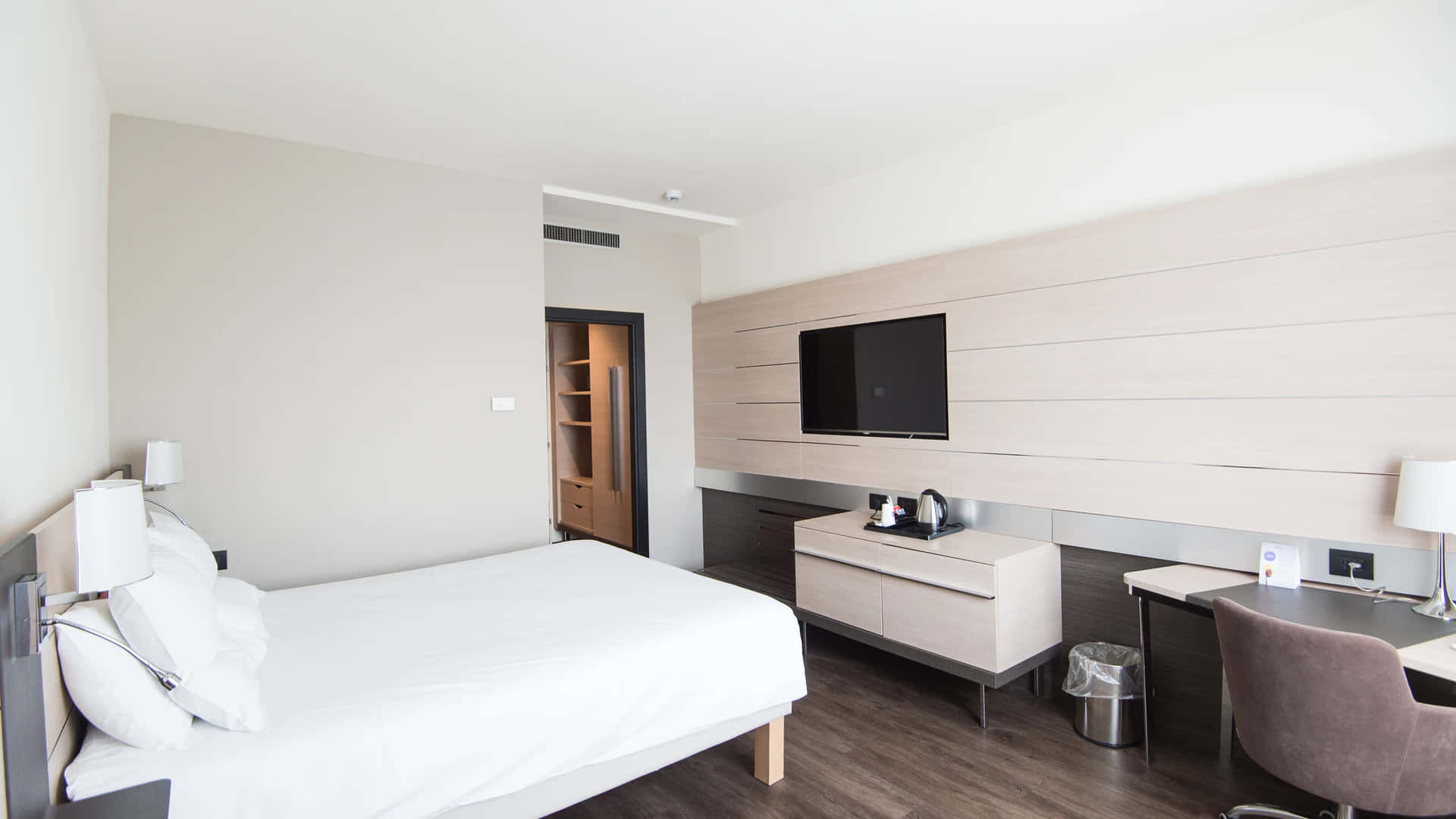 Hotel Room 桌布 壁紙 — 現代簡約飯店客房，配備白色床鋪、木地板和時尚家具，光線充足。