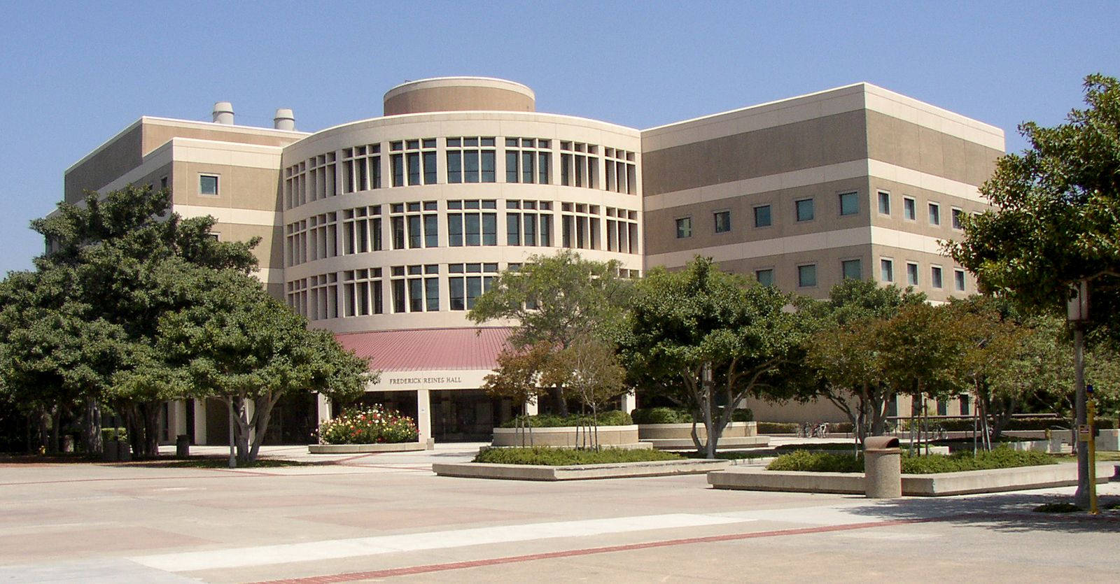 加州 桌布 壁紙 — 現代米色大學建築，採用弧形設計，在清澈藍天下有茂密的綠色樹木。