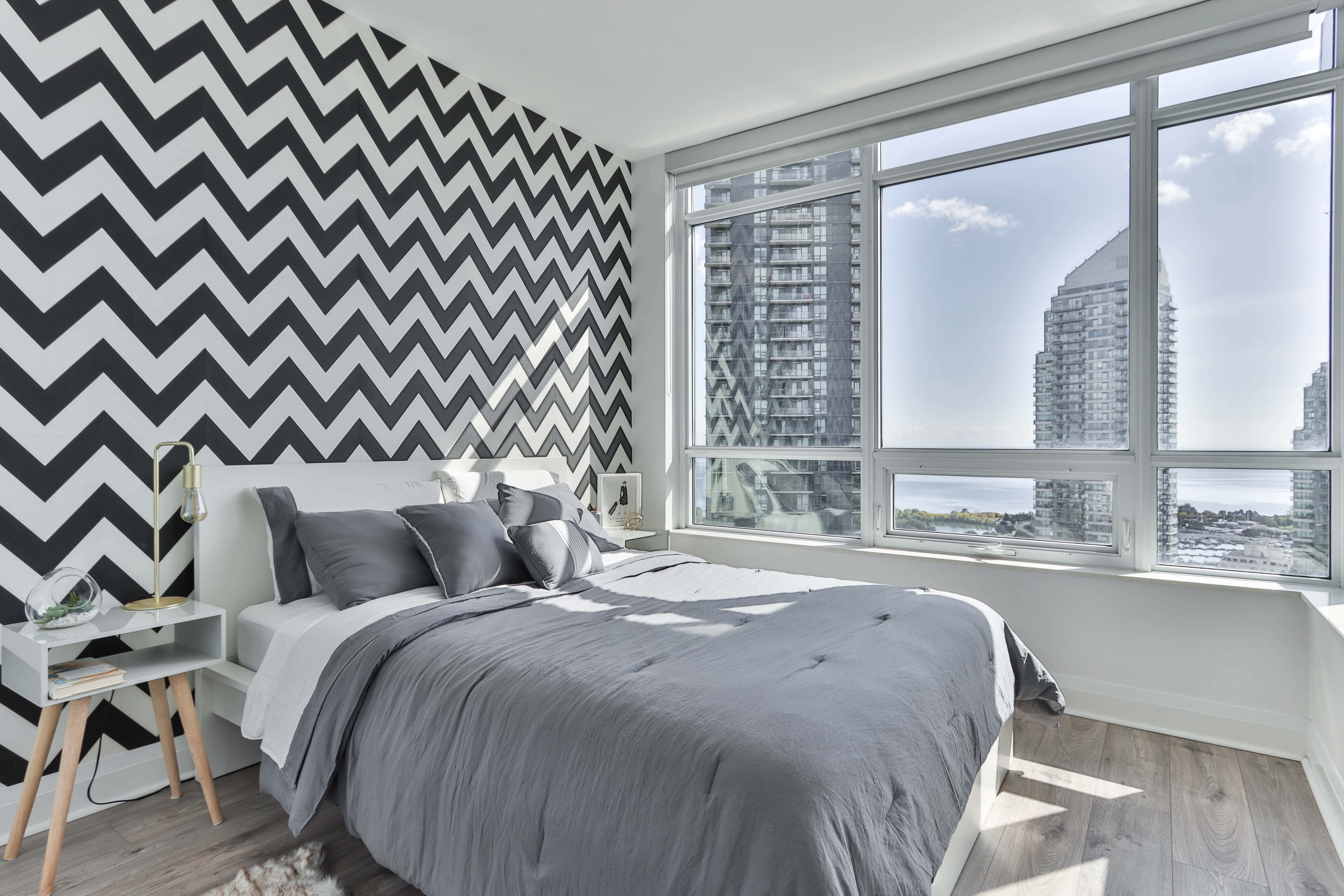 Bedroom 桌布 壁紙 — 現代臥室，配有醒目的黑白鋸齒紋壁紙，以及可俯瞰城市天際線的大窗戶。
