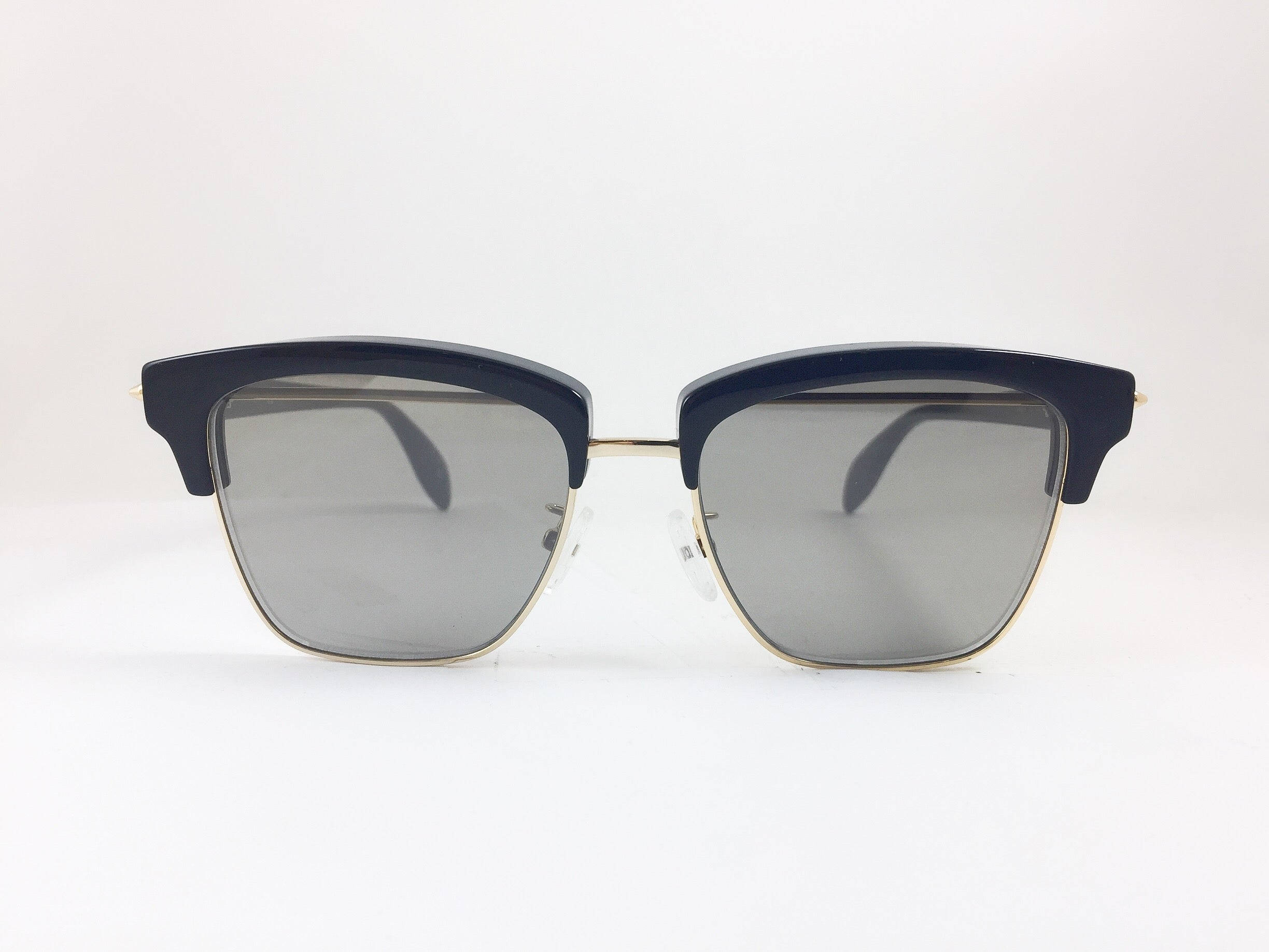 Sunglasses 桌布 壁紙 — 現代貓眼太陽眼鏡，海軍藍色鏡框搭配金色點綴，放置在潔白表面上。