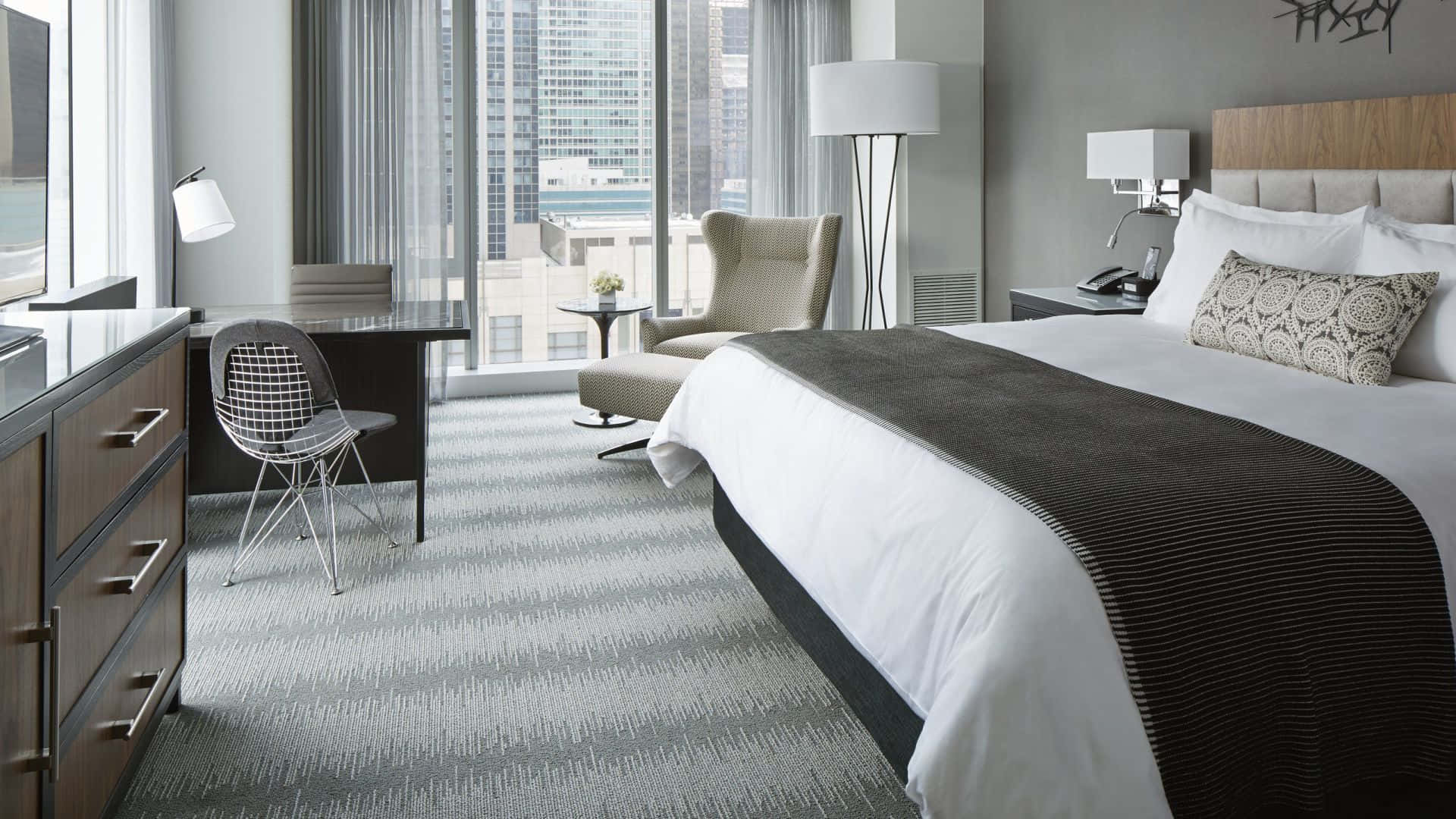 Bedroom 桌布 壁紙 — 現代酒店客房，設有大窗戶可俯瞰城市天際線，配備時尚家具和灰色圖案地毯。