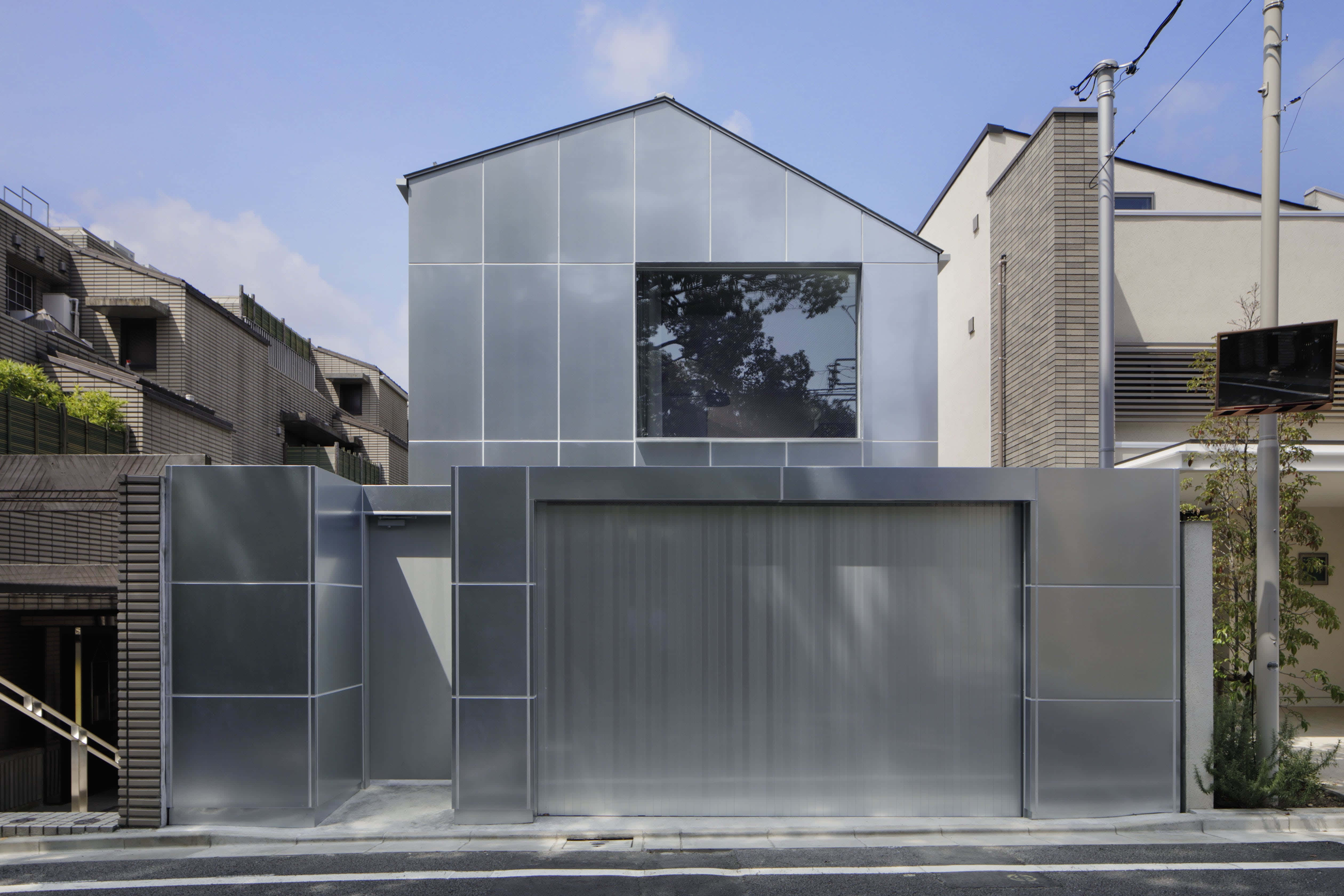 Minimalist Architecture 桌布 壁紙 — 現代銀色金屬房屋，配有大玻璃窗和車庫門，在晴朗的藍天下。