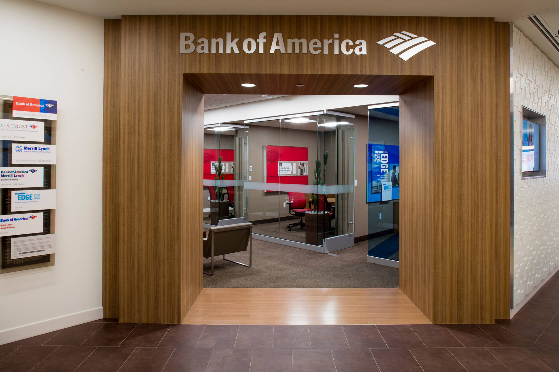 Bank 桌布 壁紙 — 現代銀行入口，採用木質鑲板和玻璃門，展現出帶有紅色點綴和數位顯示器的時尚內部。