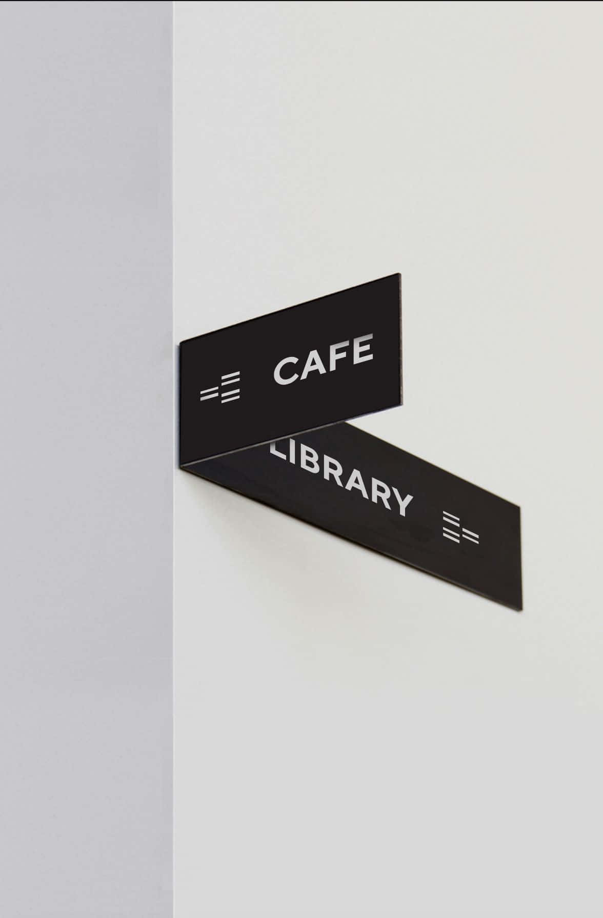 Minimalist Photography 桌布 壁紙 — 現代黑色斜角標誌，用於咖啡館和圖書館，安裝在簡約白色牆壁上。