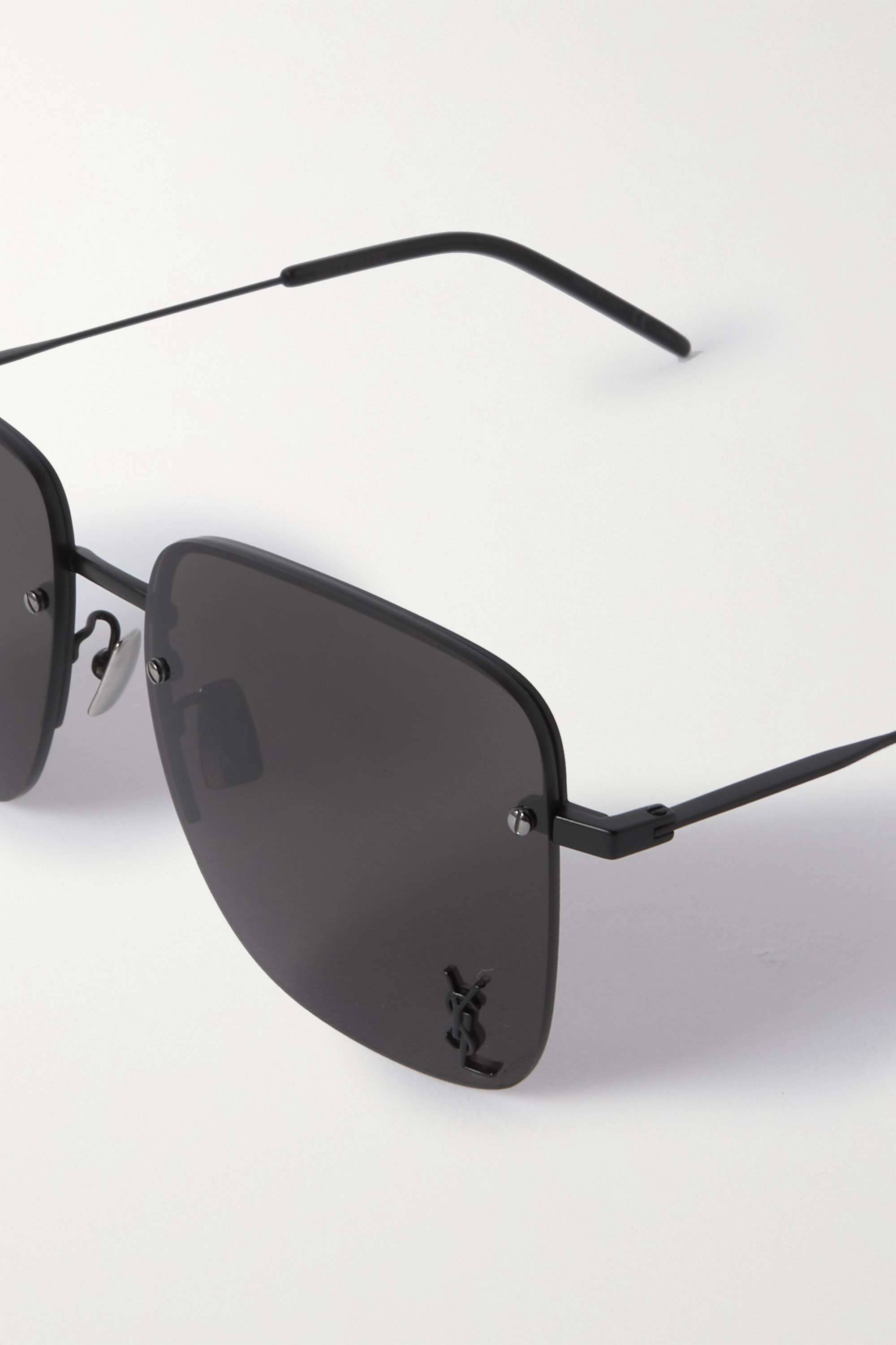 saint laurent 桌布 壁紙 — 現代黑色無框太陽眼鏡，深灰色鏡片，帶有YSL標誌，放置在潔白的表面上。