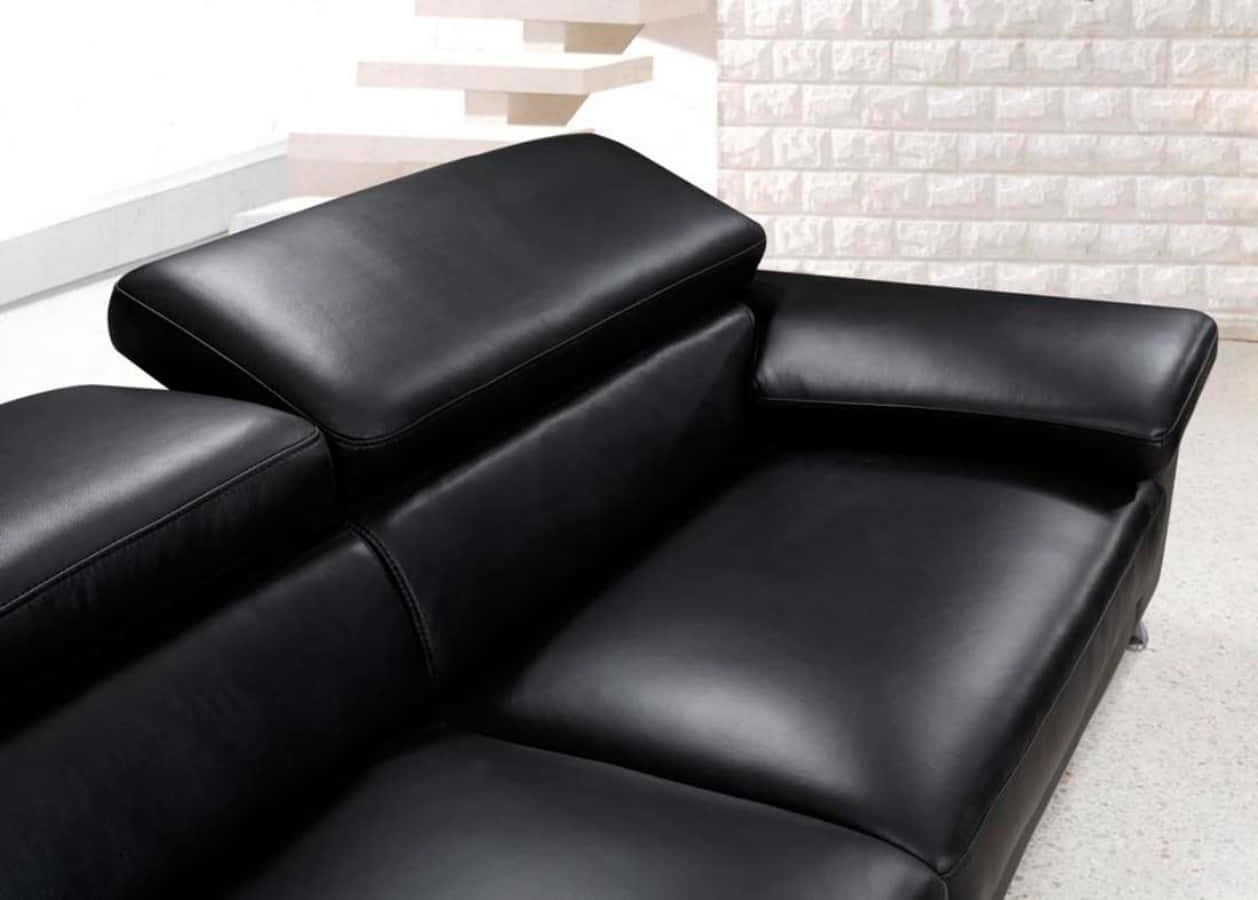 Black Leather 桌布 壁紙 — 現代黑色皮革組合沙發，設計時尚，置於簡約房間內，配有白色磚牆和懸浮樓梯。