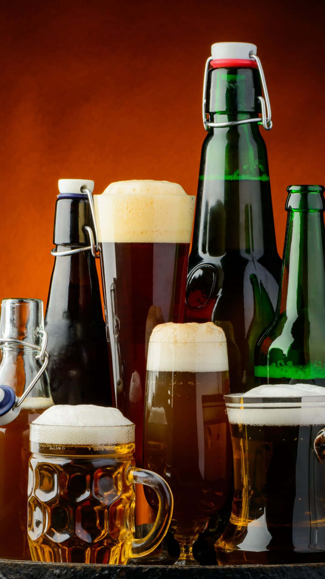 Beer 桌布 壁紙 — 琥珀色啤酒杯和綠色玻璃瓶在溫暖的陶土背景前，帶有泡沫頂部的豐富照明排列。