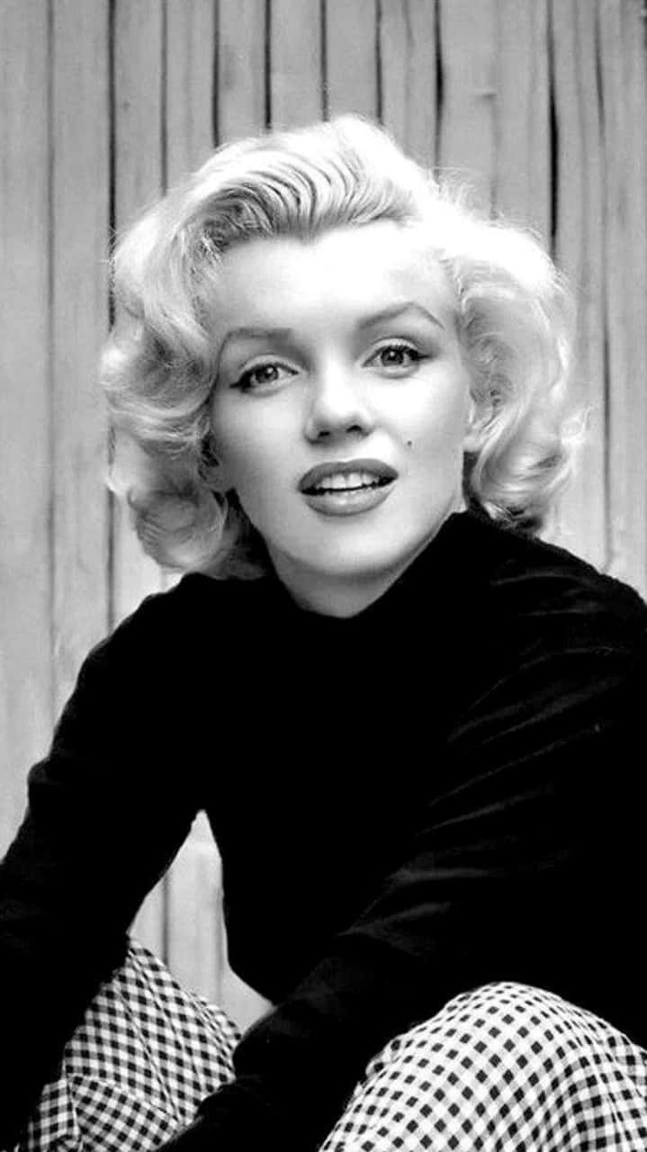 Marilyn Monroe iPhone 桌布 壁紙 — 瑪麗蓮夢露在木鑲板牆前，以經典黑白肖像溫柔微笑。