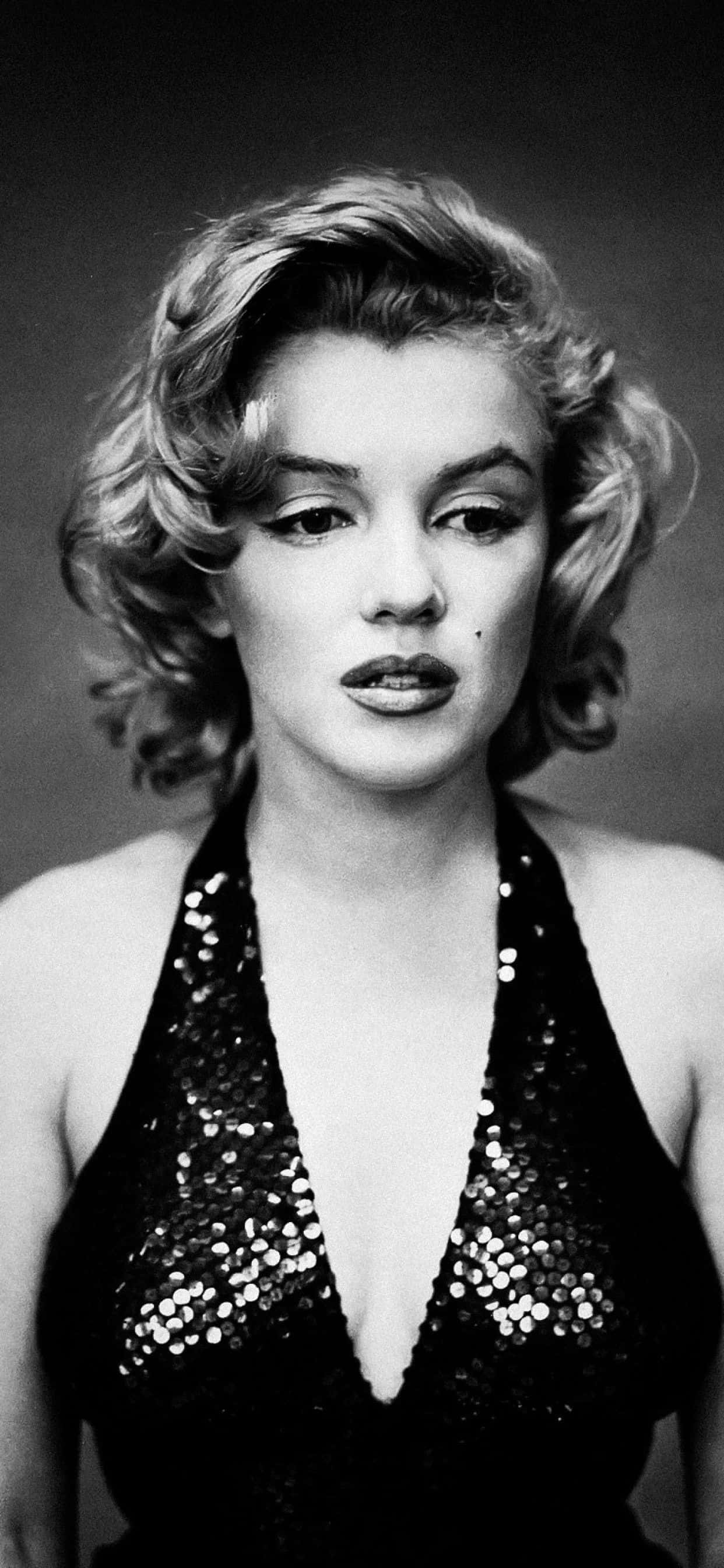 Marilyn Monroe iPhone 桌布 壁紙 — 瑪麗蓮夢露身穿黑色亮片掛頸上衣，在簡約的攝影棚背景下，直接凝視鏡頭，表情嫵媚。