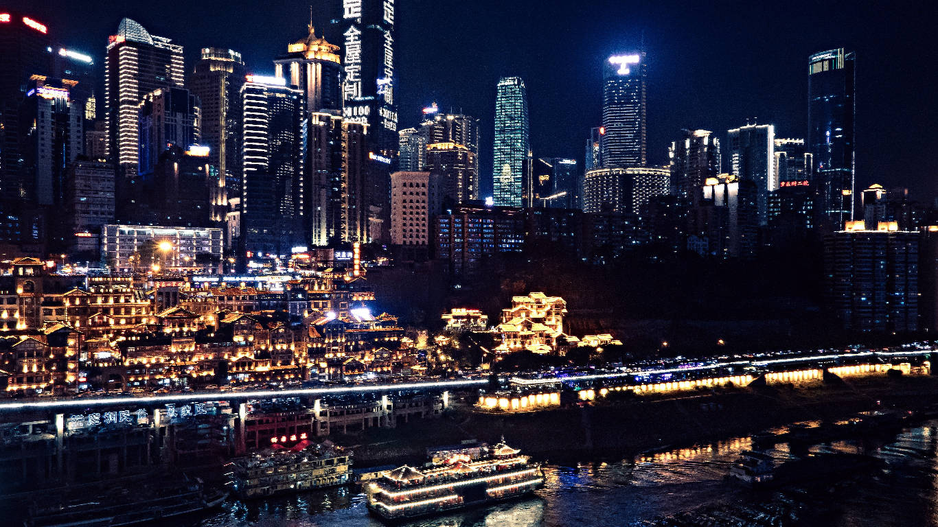 Chongqing 桌布 壁紙 — 璀璨的夜景，摩天大樓和傳統建築沿河而立，河上還有燈火通明的船隻。