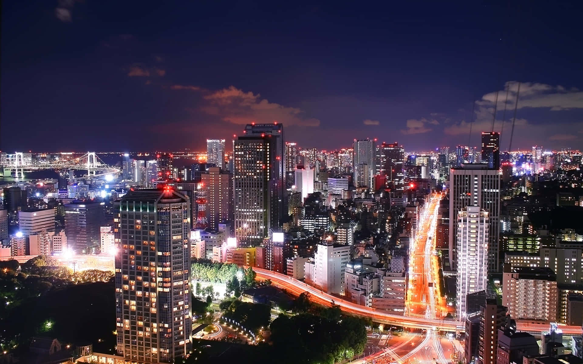 東京 桌布 壁紙 — 璀璨的夜景城市景觀，閃爍的摩天大樓和流動的車燈照亮了城市廣闊的空間。