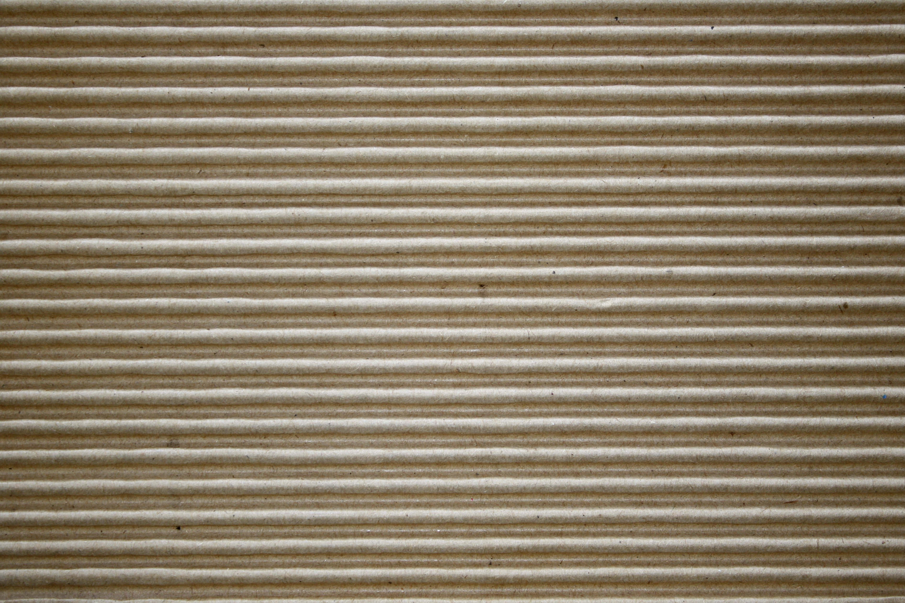 cardboard 桌布 壁紙 — 瓦楞紙板紋理的近距離特寫，帶有平行脊線和自然棕色色調。