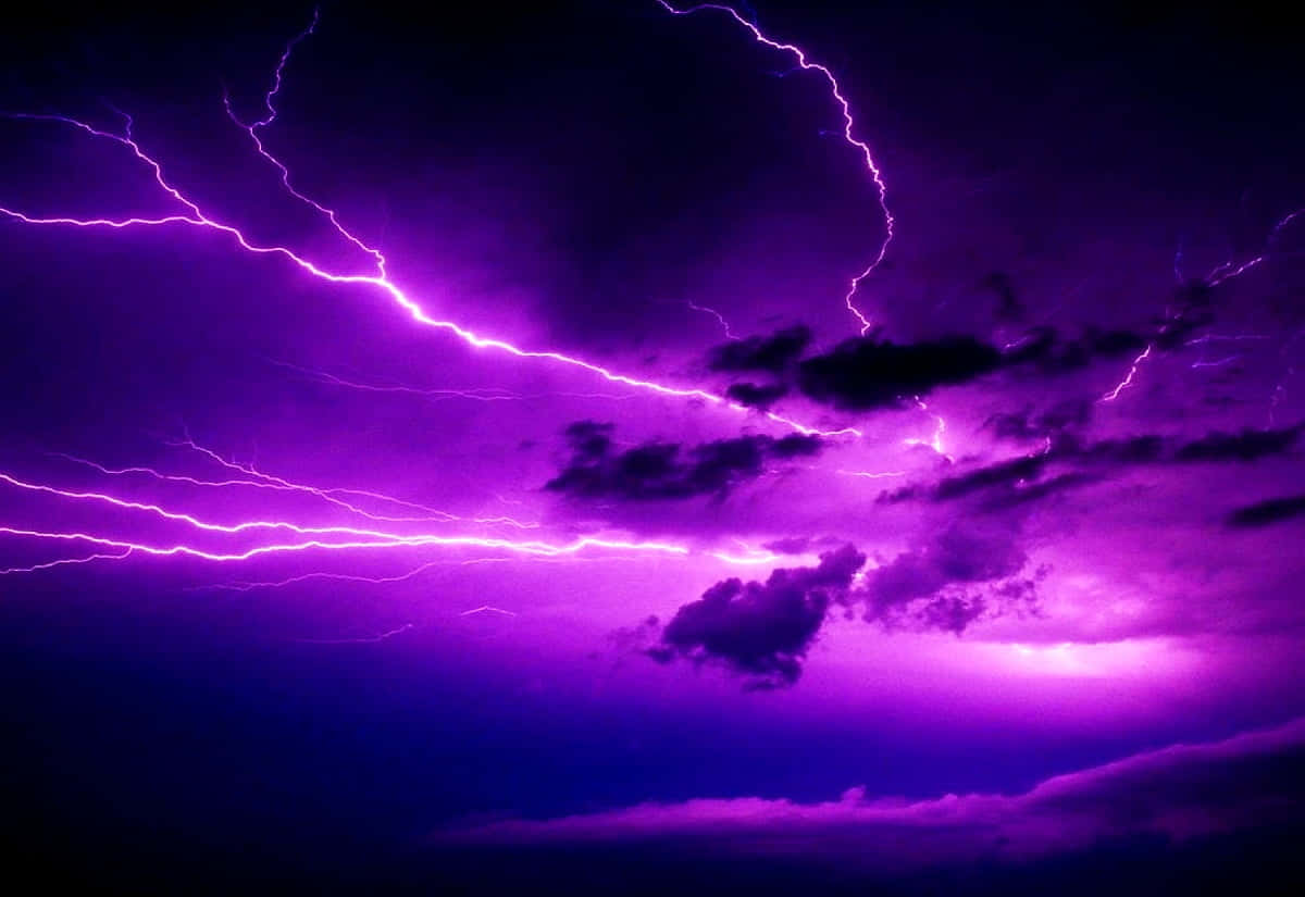閃電 桌布 壁紙 — 生動的紫色閃電在暴風雨的天空中分叉，照亮了烏雲，形成戲劇性的電光展示。