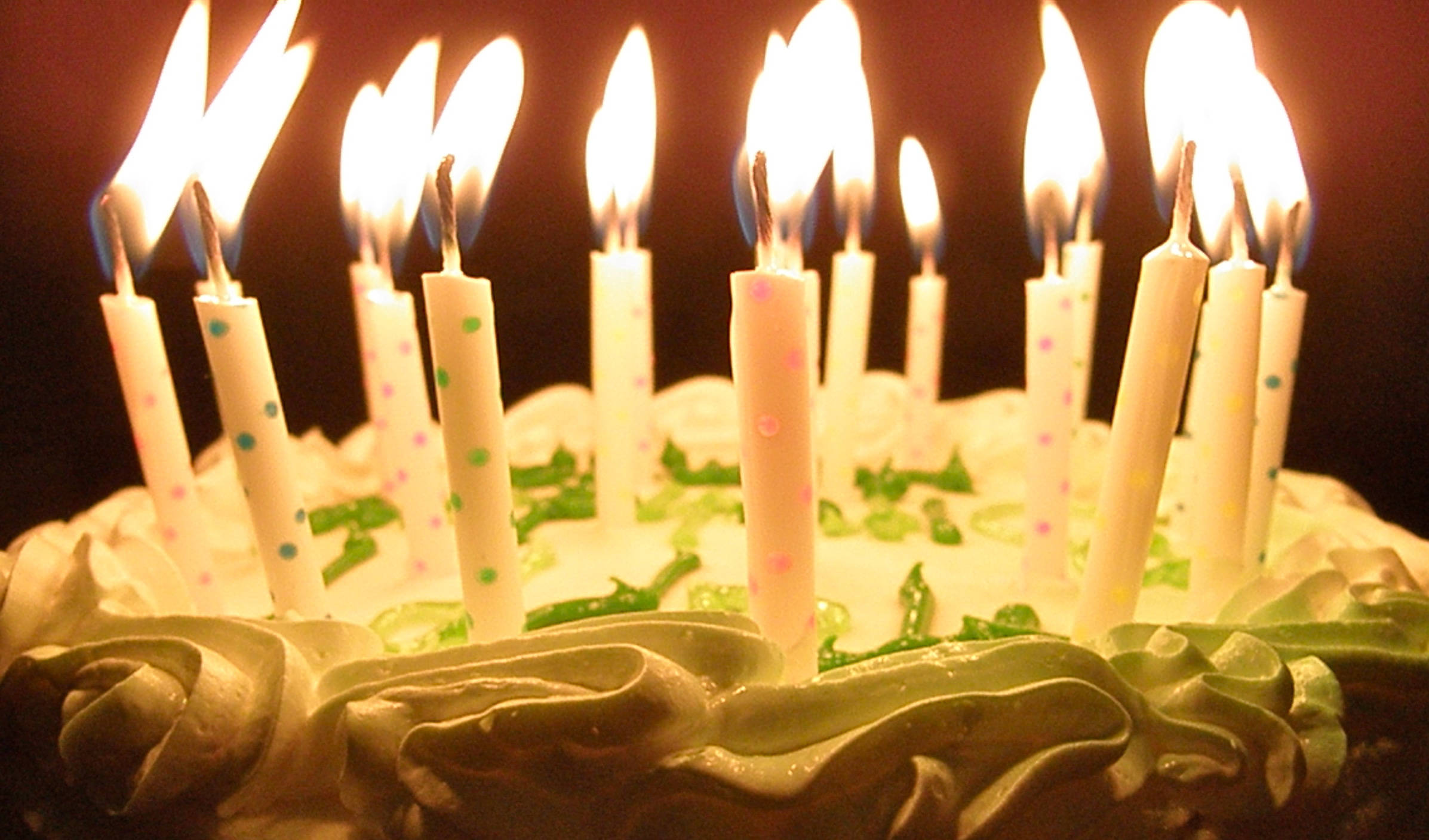 Cake 桌布 壁紙 — 生日蛋糕特寫，蠟燭點燃，在黑暗背景下投射出溫暖的光芒。