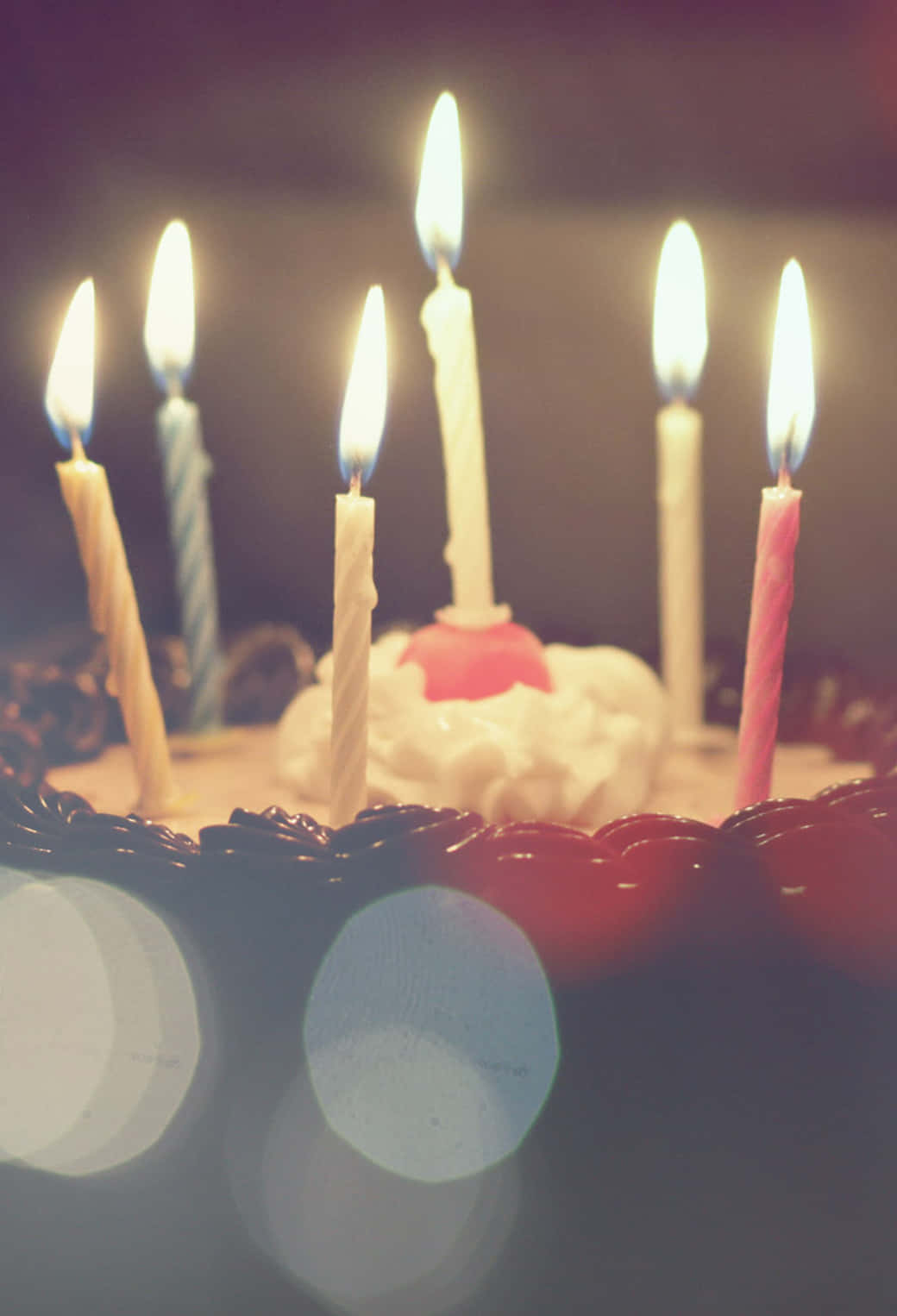 Birthday Cake 桌布 壁紙 — 生日蛋糕的特寫，點燃的蠟燭在模糊的背景上投射出溫暖的光芒，帶有散景效果。