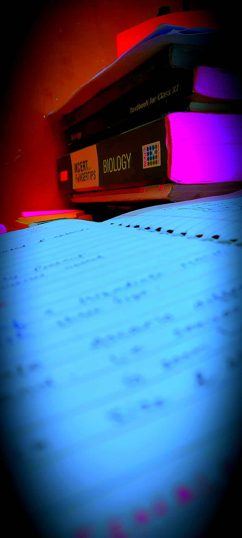 Educated 桌布 壁紙 — 生物教科書和手寫筆記的特寫，沐浴在戲劇性的紅藍燈光中。