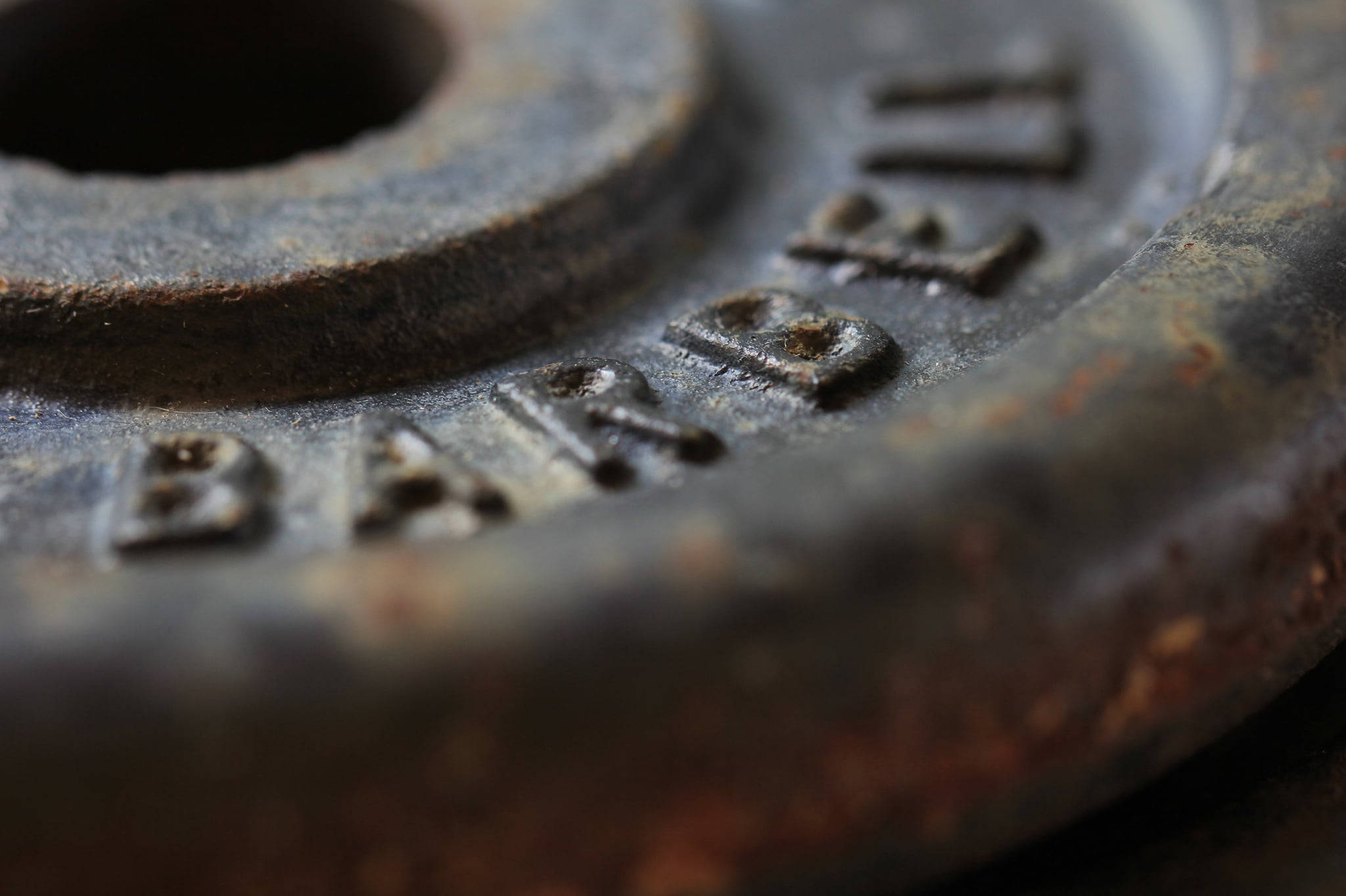 Barbell 桌布 壁紙 — 生鏽槓鈴片的特寫，帶有浮雕文字，顯示因重複使用而造成的磨損。