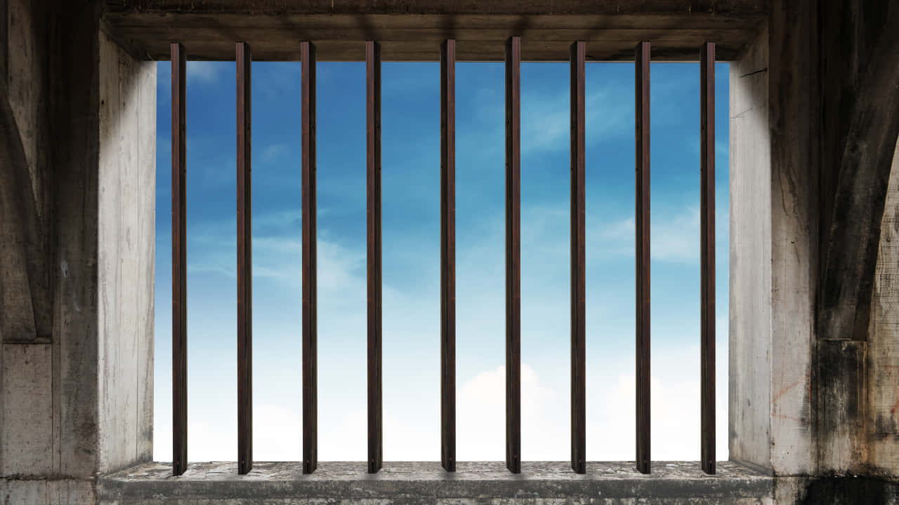 Prison Cell 桌布 壁紙 — 生鏽的金屬條框住透過風化混凝土窗開口可見的清澈藍天。