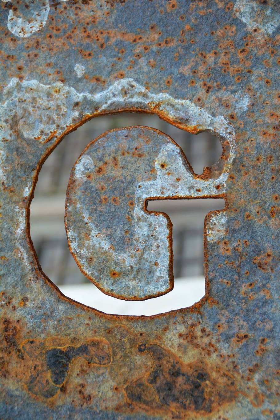 g 桌布 壁紙 — 生鏽金屬字母G的特寫，帶有風化紋理和橙褐色腐蝕，背景模糊。