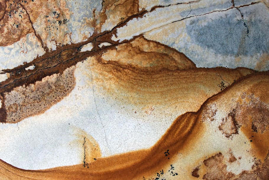 Brown Marble 桌布 壁紙 — 生鏽金屬表面的特寫，呈現旋轉的棕黃色和灰色紋理，顯露風化後的銅綠。