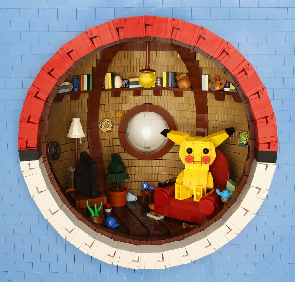 精靈球 桌布 壁紙 — 用LEGO建造的哈比人洞穴內部，皮卡丘坐在紅色扶手椅上，周圍環繞著書籍和裝飾品。