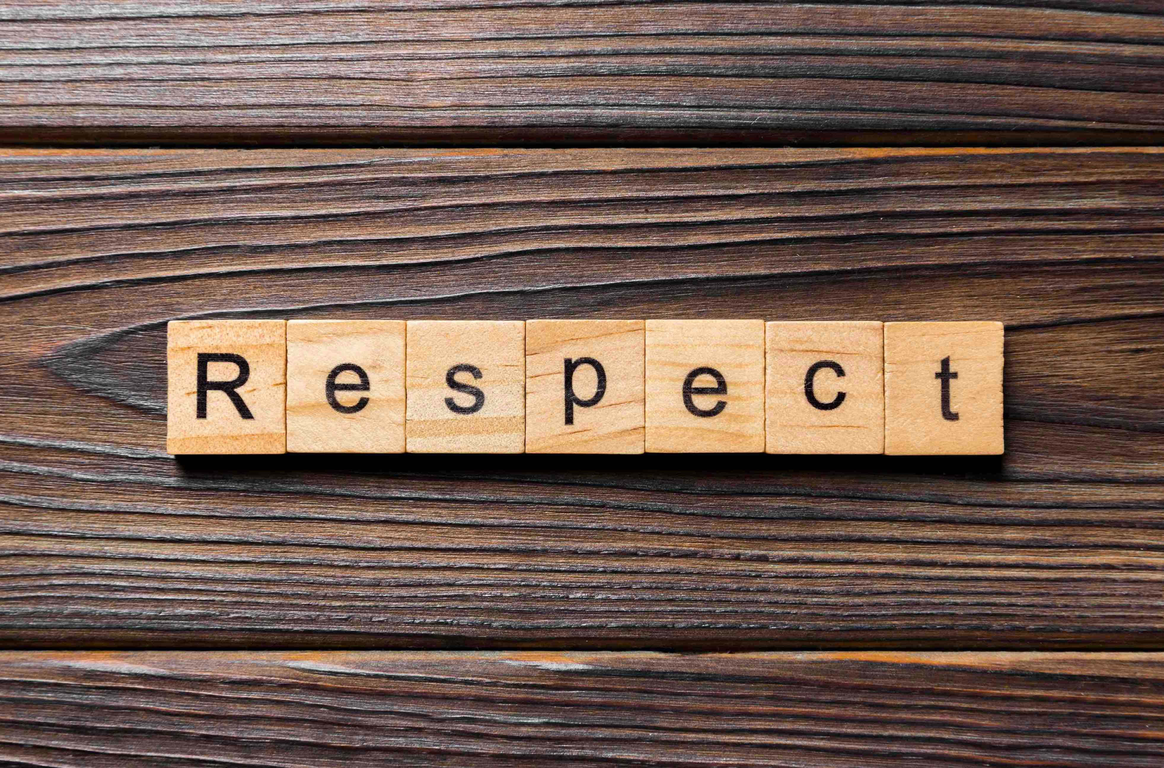 設計 桌布 壁紙 — 用木製字母瓷磚拼寫的「Respect」一詞，放置在深色紋理木質表面上。
