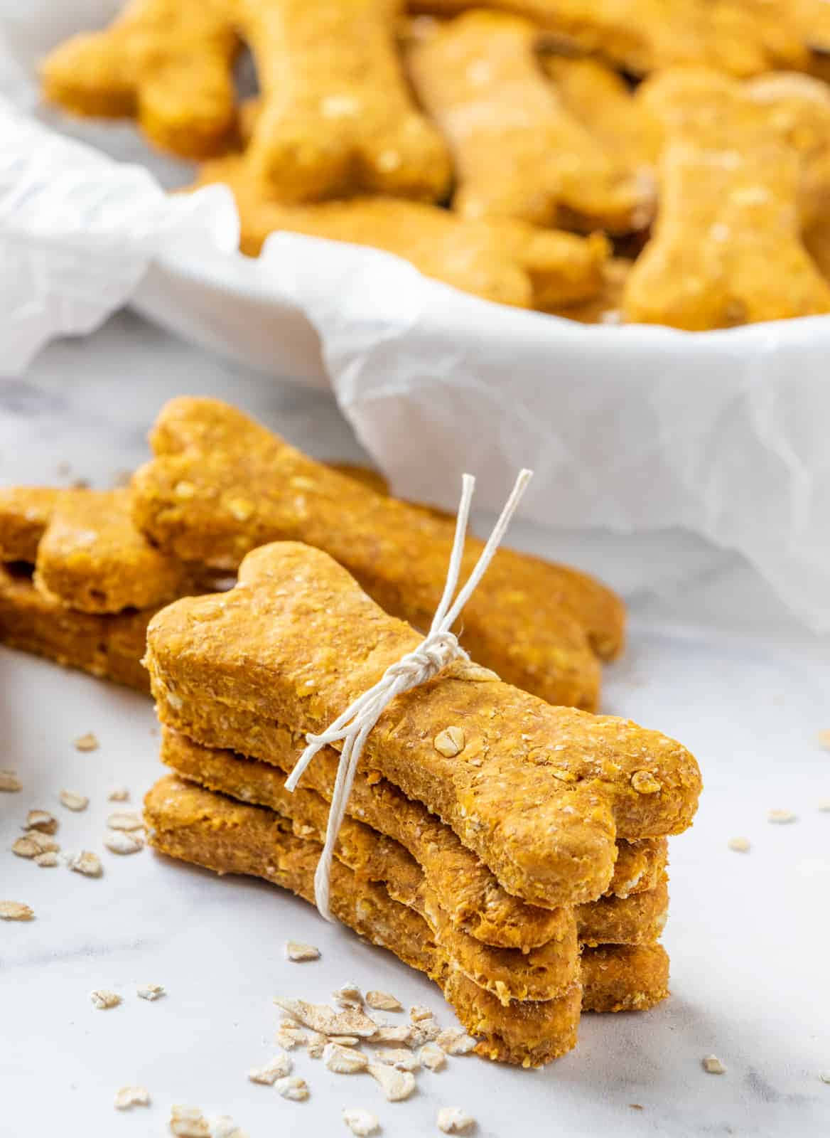 Cookies 桌布 壁紙 — 用麻繩捆綁的骨形狗零食堆疊在大理石表面上，後面一個白色碗裡散落著燕麥片和更多零食。
