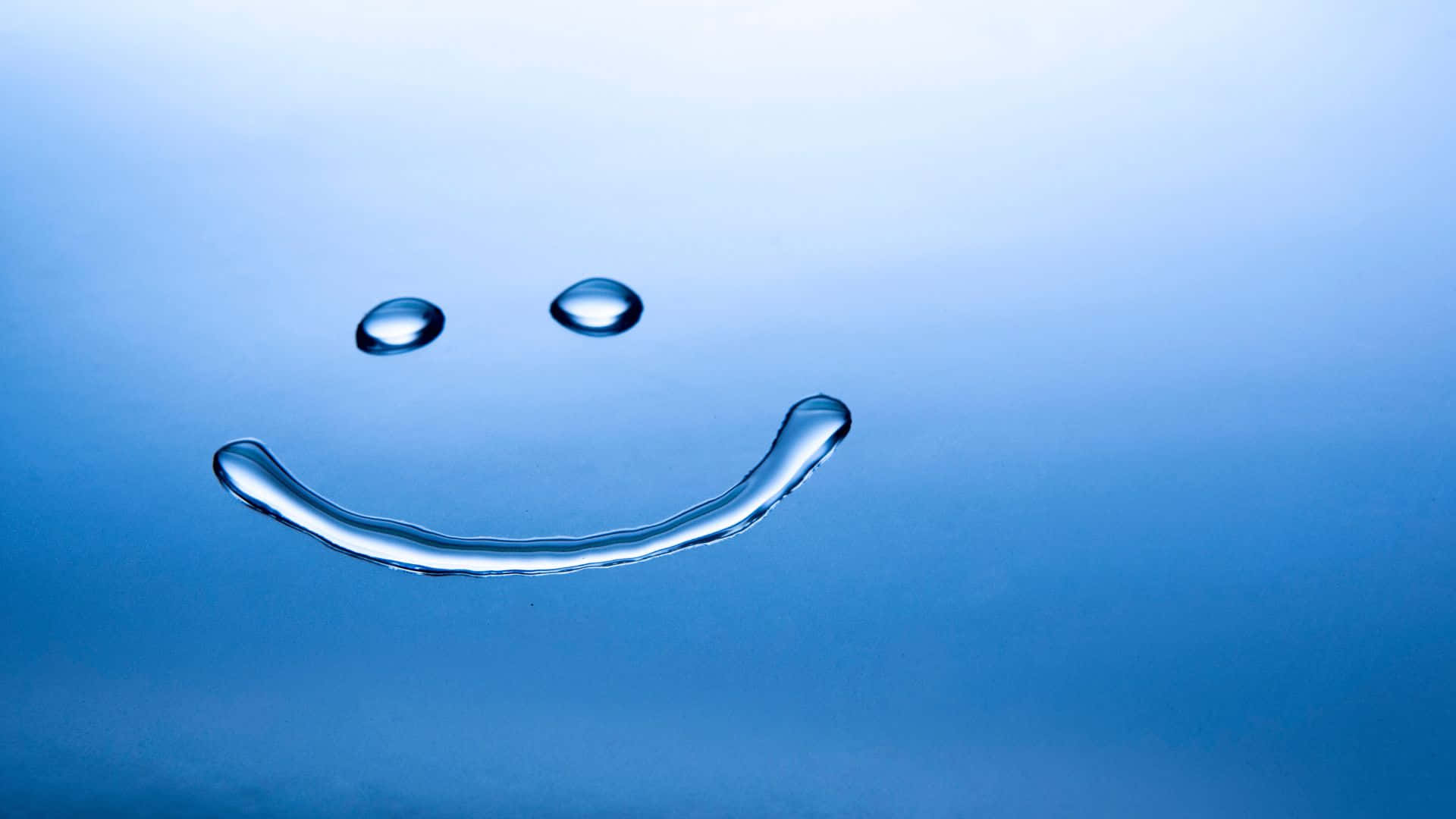 Smiley 桌布 壁紙 — 由水滴在光滑的藍色表面上形成的歡樂笑臉。