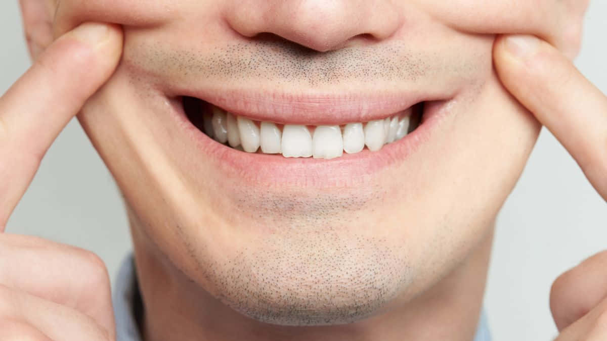 Smile 桌布 壁紙 — 男子微笑臉部的特寫，手指輕輕向上拉臉頰，以展示柔軟肌膚上明亮的白色牙齒。