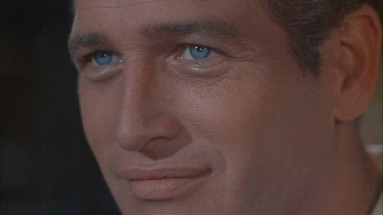 newman 桌布 壁紙 — 男子臉部特寫，擁有引人注目的藍色眼睛和微妙的微笑，在昏暗的燈光下。