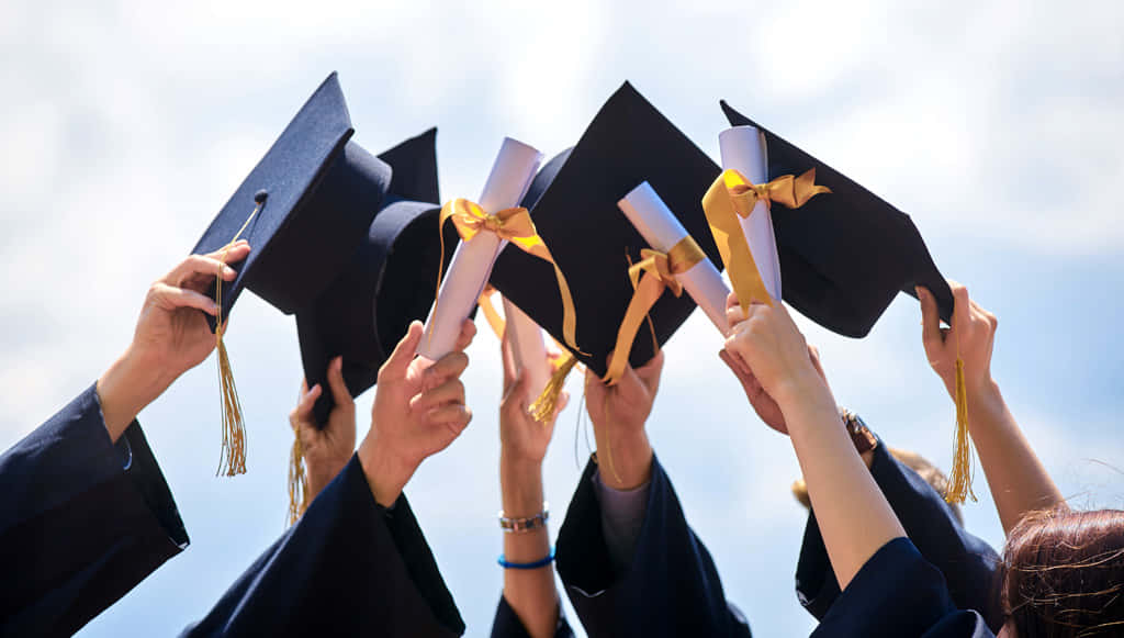 Graduation 桌布 壁紙 — 畢業生們在明亮的藍天下，高興地將黑色學士帽和文憑拋向空中。