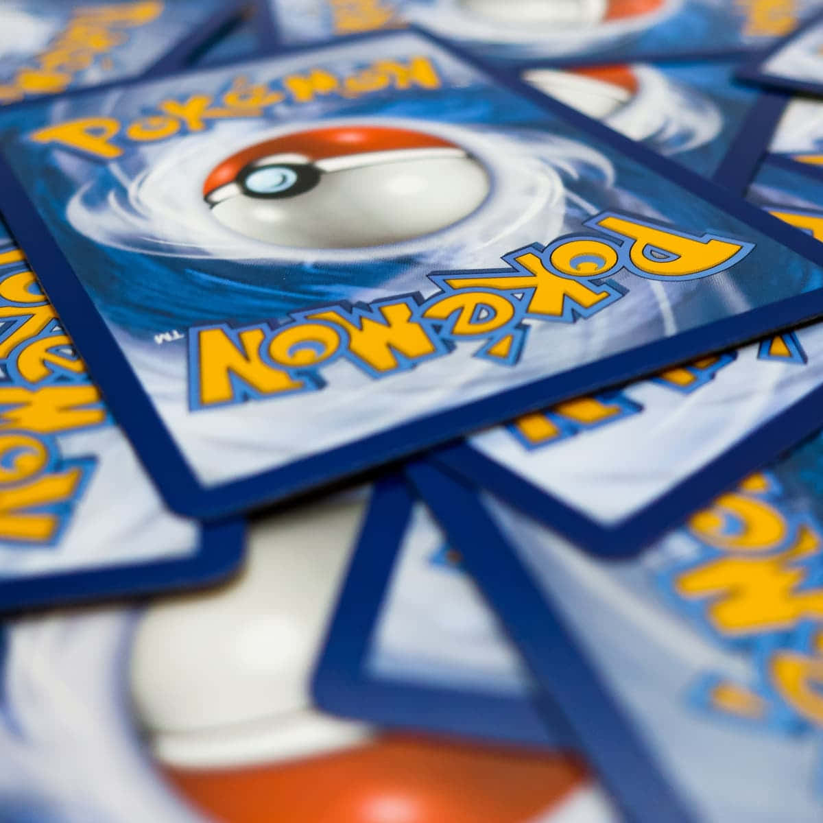 Pokemon Card 桌布 壁紙 — 疊起的寶可夢集換式卡牌特寫，印有帶藍色漩渦和黃色文字的寶貝球標誌。