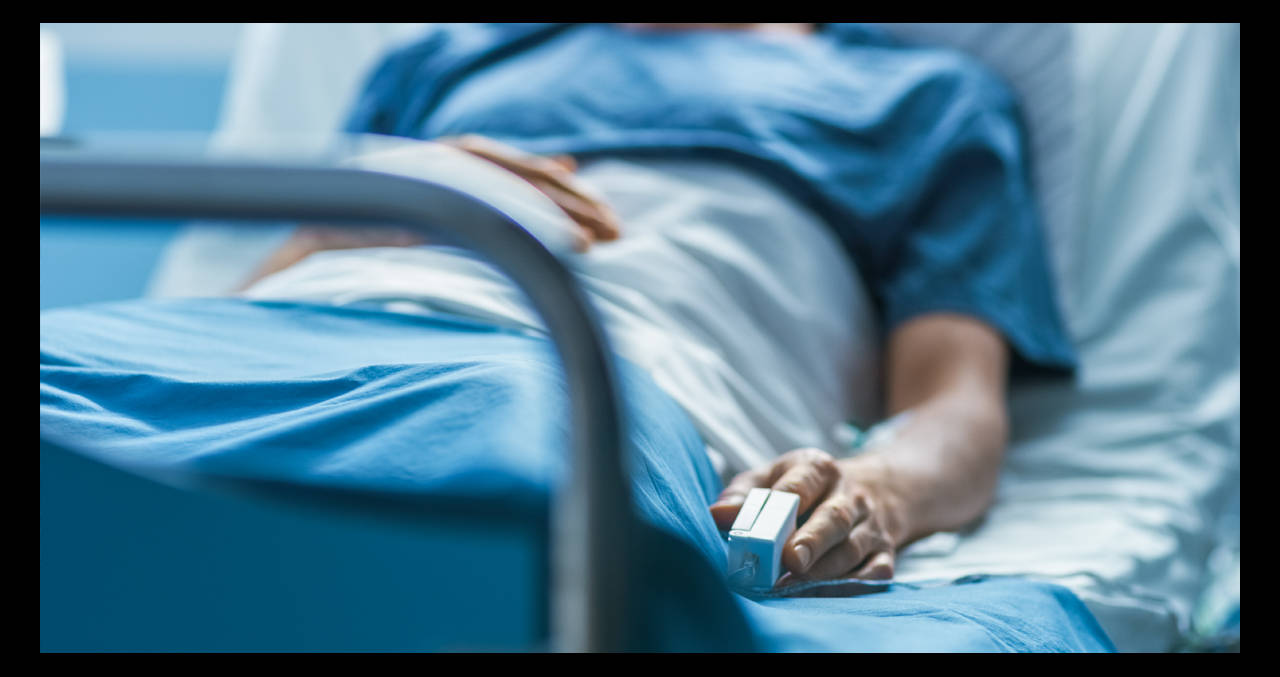 Hospital 桌布 壁紙 — 病人手部特寫，放在醫院床上，夾著脈搏血氧儀，蓋著藍色床單。