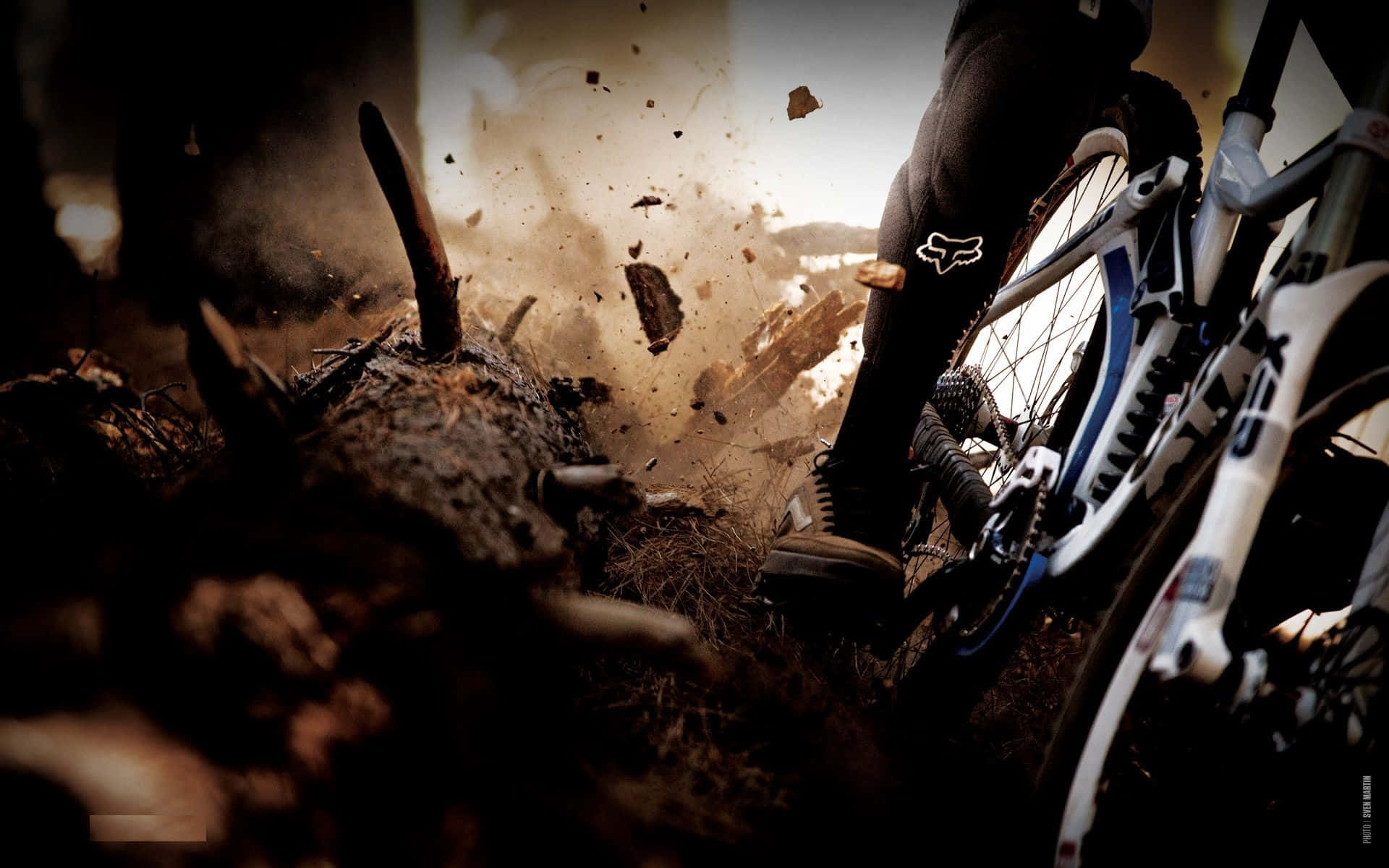 Mtb 桌布 壁紙 — 登山車靴踢起泥土和碎屑，自行車前輪在泥濘地形中濺起水花。