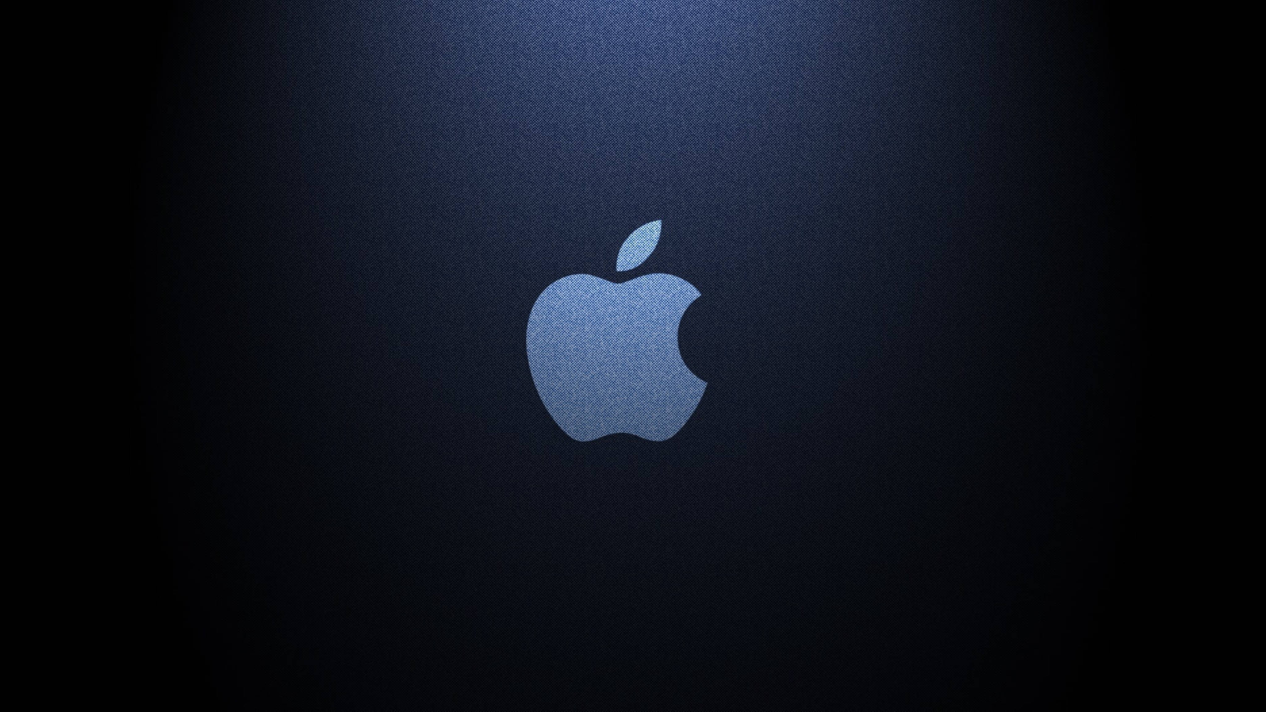 Apple 4K Ultra HD 桌布 壁紙 — 發光的Apple標誌居中在深藍色紋理背景上，帶有聚光燈效果。
