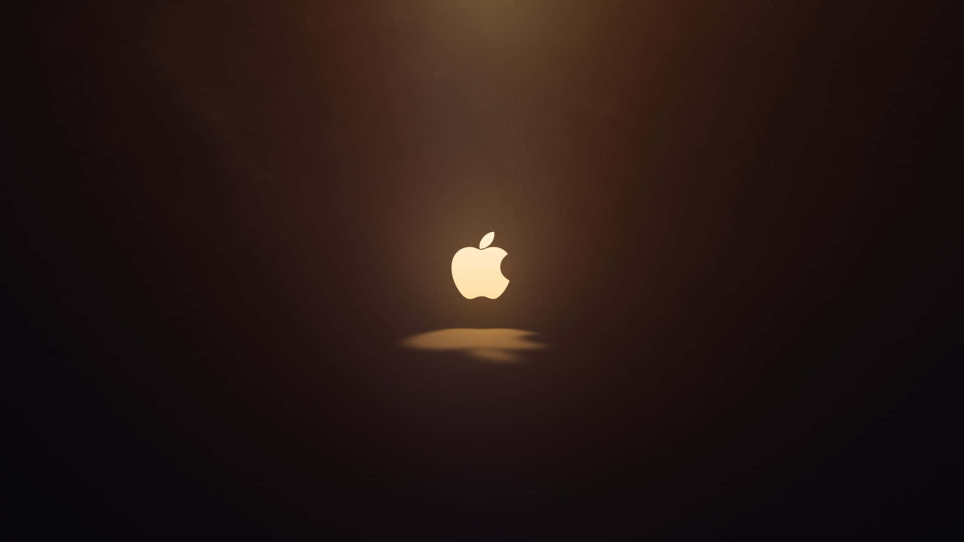 標誌 桌布 壁紙 — 發光的Apple標誌置於黑暗中央，帶有柔和的金色光芒和下方微妙的陰影。