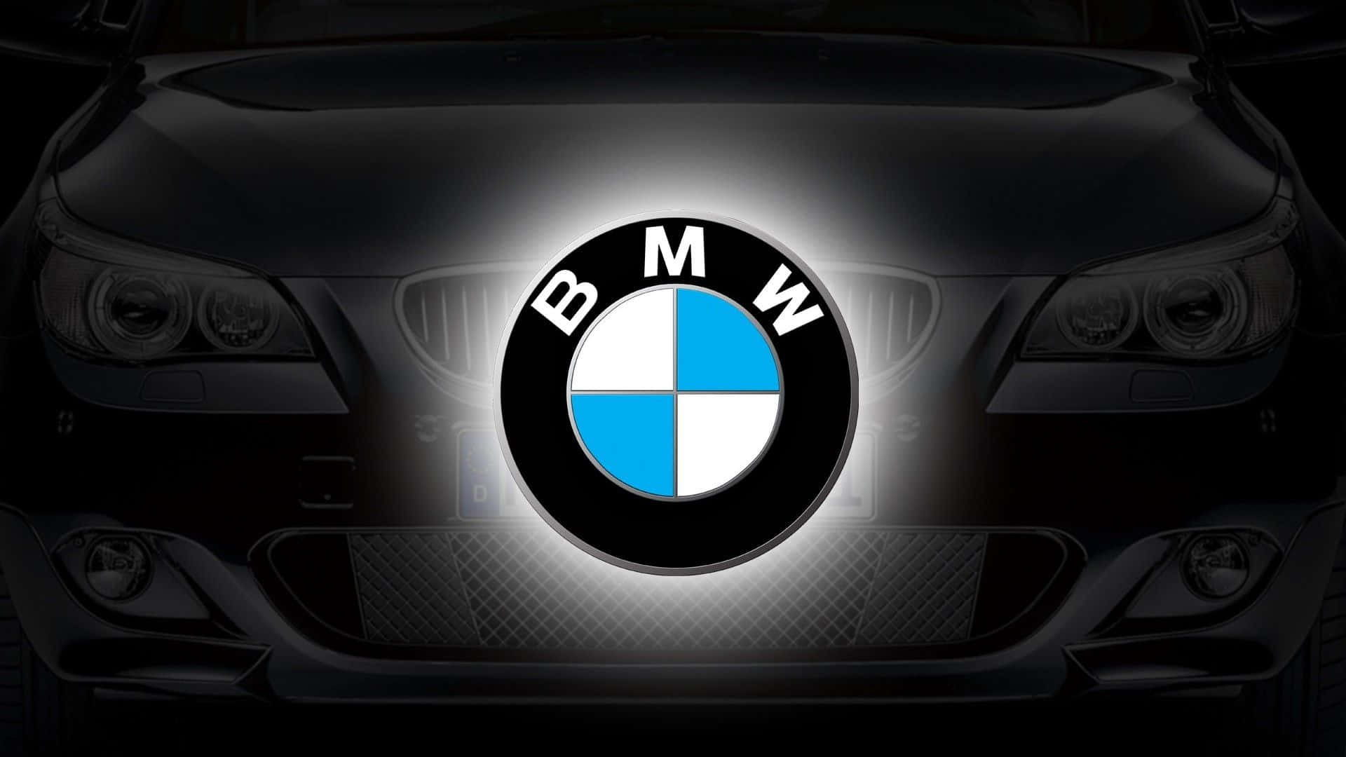 Bmw Laptop 桌布 壁紙 — 發光的BMW標誌位於深色引擎蓋中央，車頭燈在陰影中隱約可見。