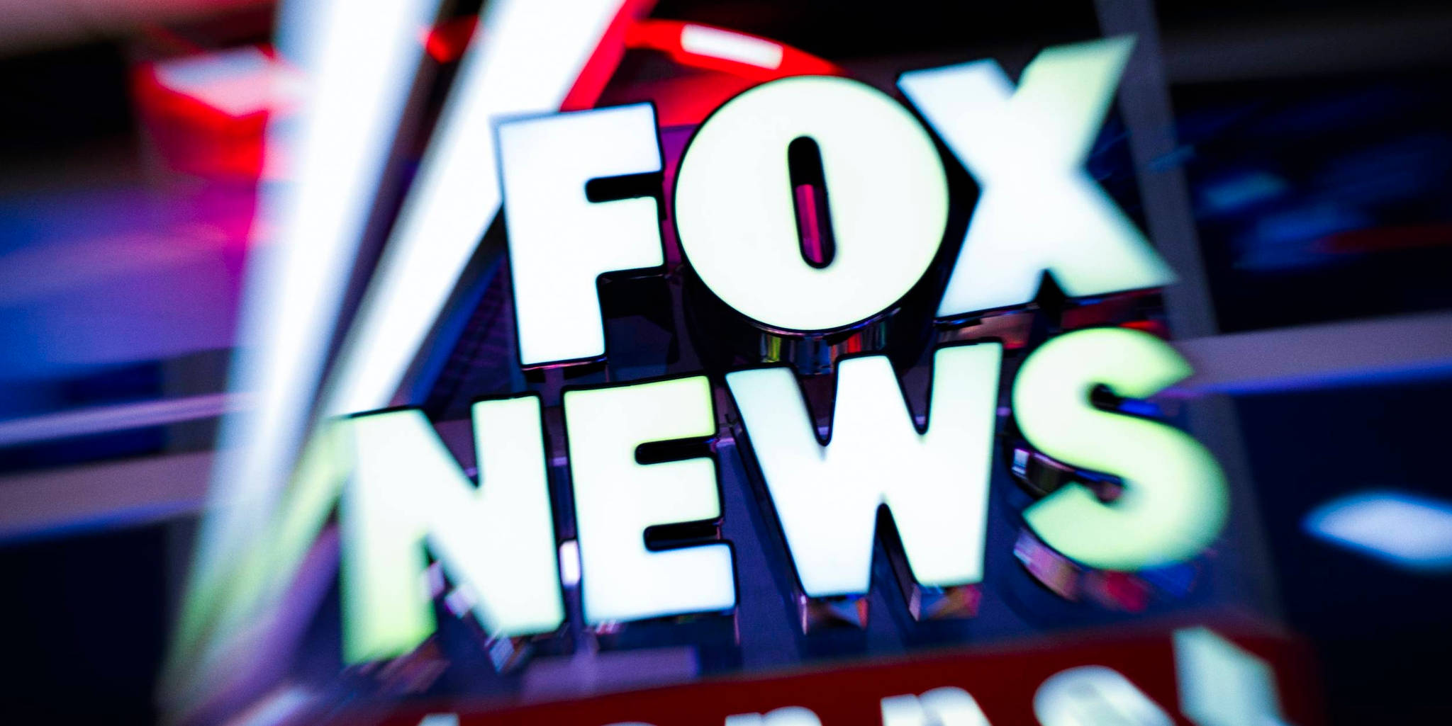 News 桌布 壁紙 — 發光的Fox News頻道標誌特寫，配有鮮豔的霓虹燈和模糊的工作室背景。