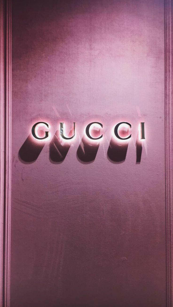Gucci iPhone 桌布 壁紙 — 發光的Gucci標誌以粗體字母在帶有紋理的灰紫色牆壁上投射出戲劇性的陰影，牆壁由優雅的線板框起。