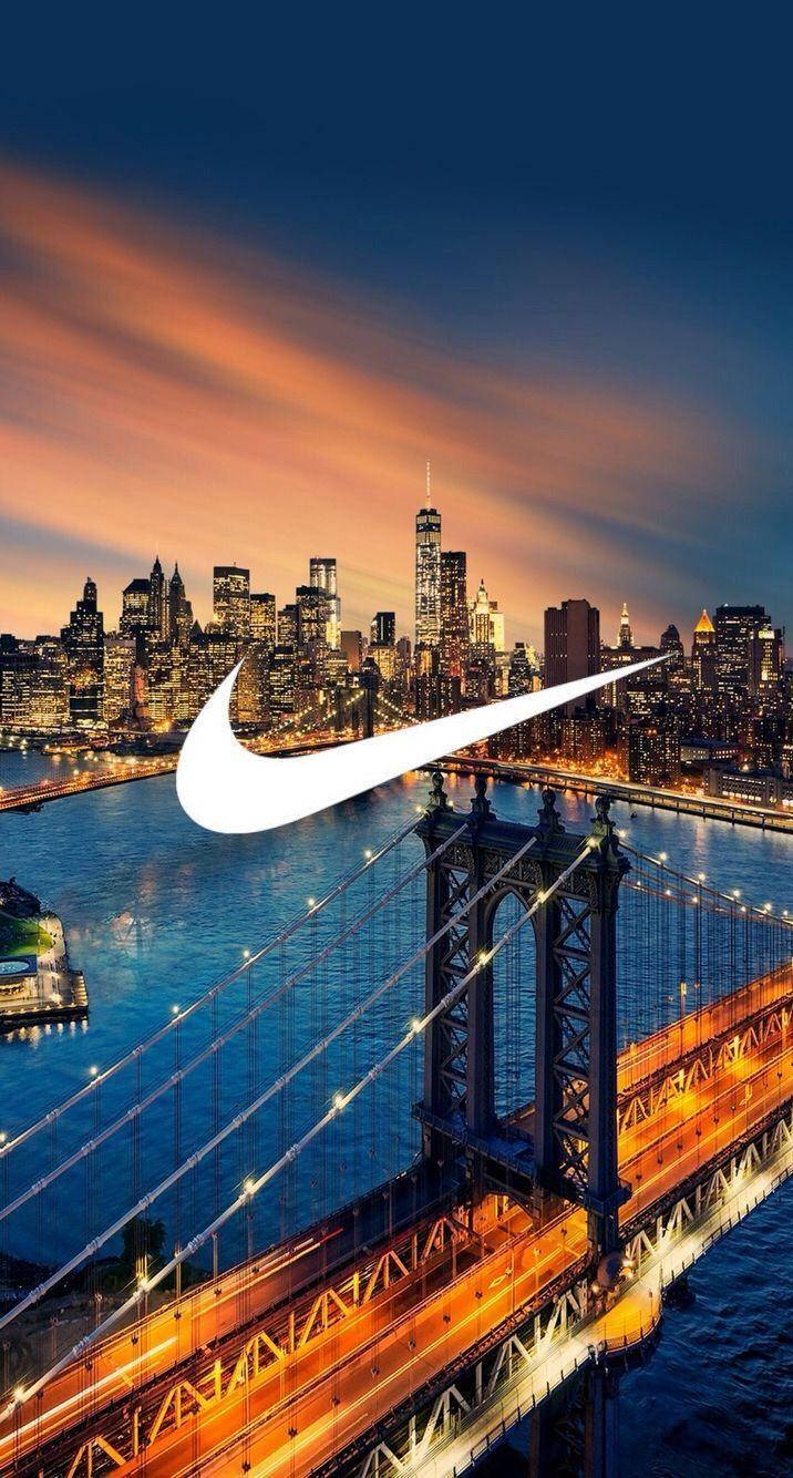Nike iPhone 桌布 壁紙 — 發光的Nike標誌疊加在布魯克林大橋和曼哈頓天際線上的鮮豔日落。