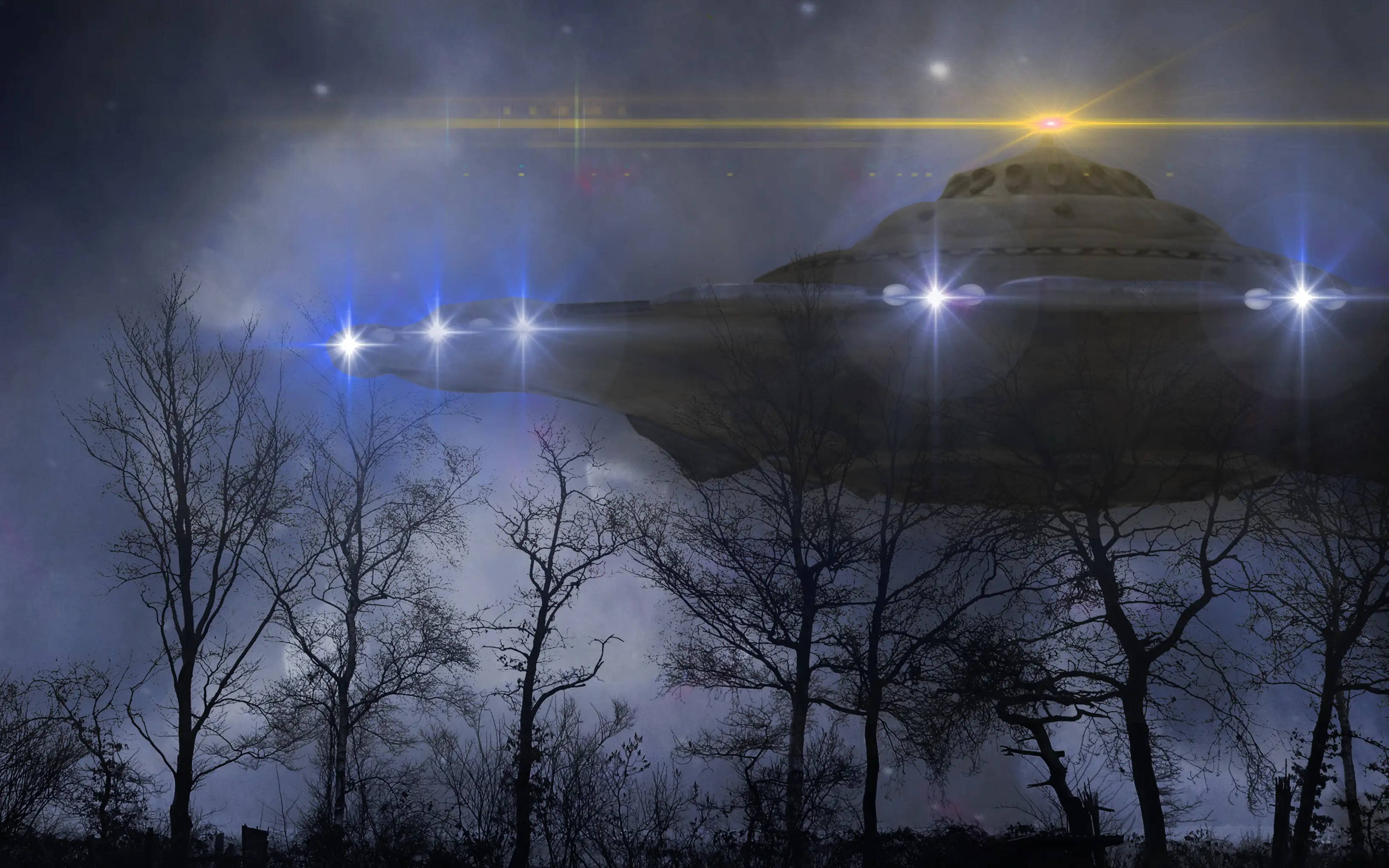 幽浮 桌布 壁紙 — 發光的UFO在繁星點點的夜空下，懸浮在光禿禿的樹木上方，帶有明亮的鏡頭眩光。