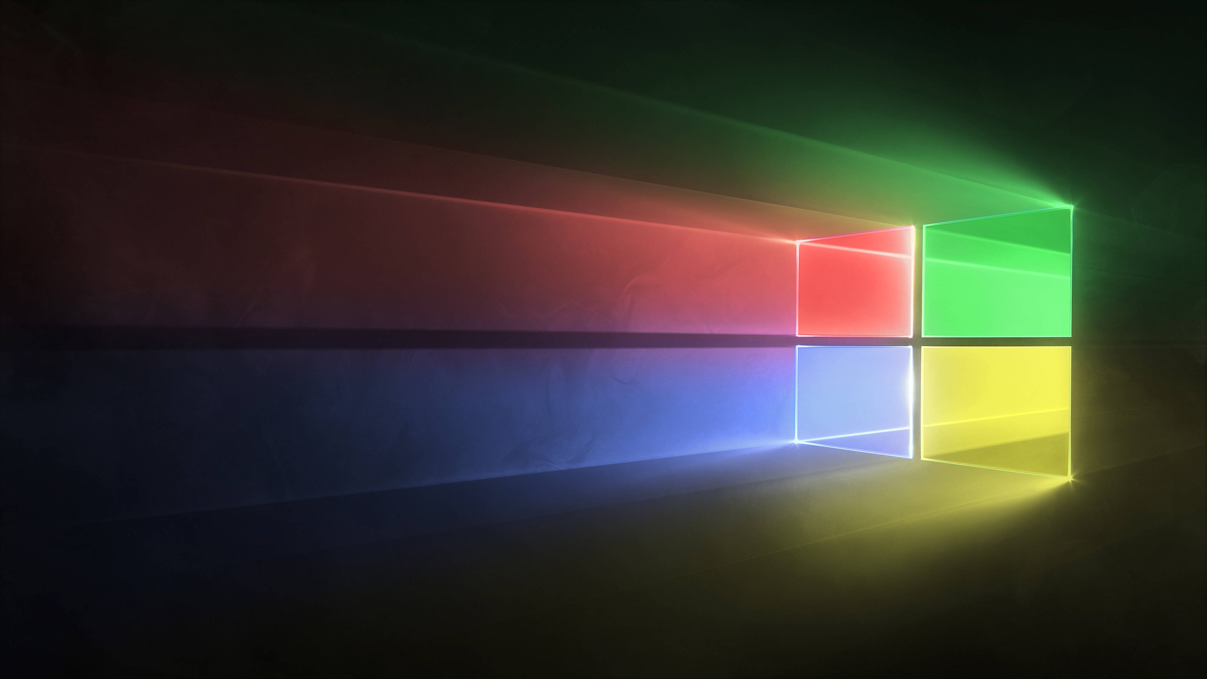Windows 10 高畫質 桌布 壁紙 — 發光的Windows標誌在深色紋理牆壁上投射出鮮豔的紅、綠、藍和黃色光束。
