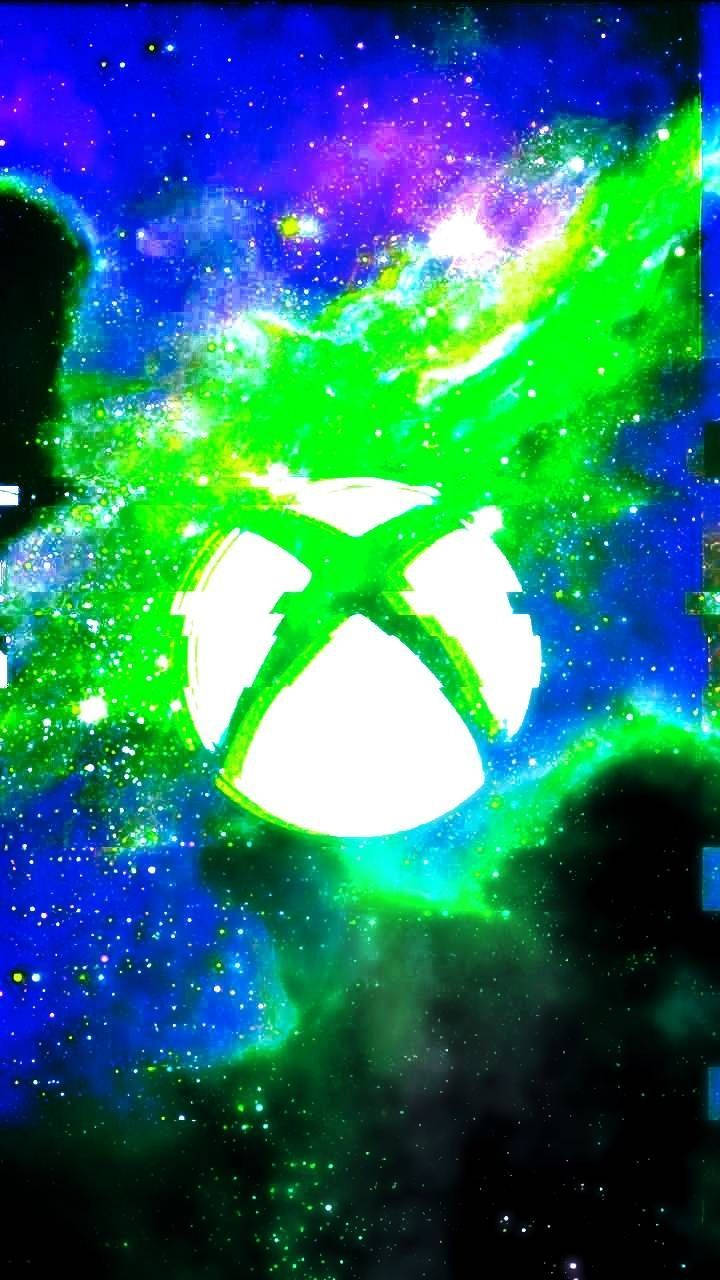 Xbox 桌布 壁紙 — 發光的Xbox標誌在紫色、藍色和星空的宇宙星雲中散發出明亮的綠色能量。