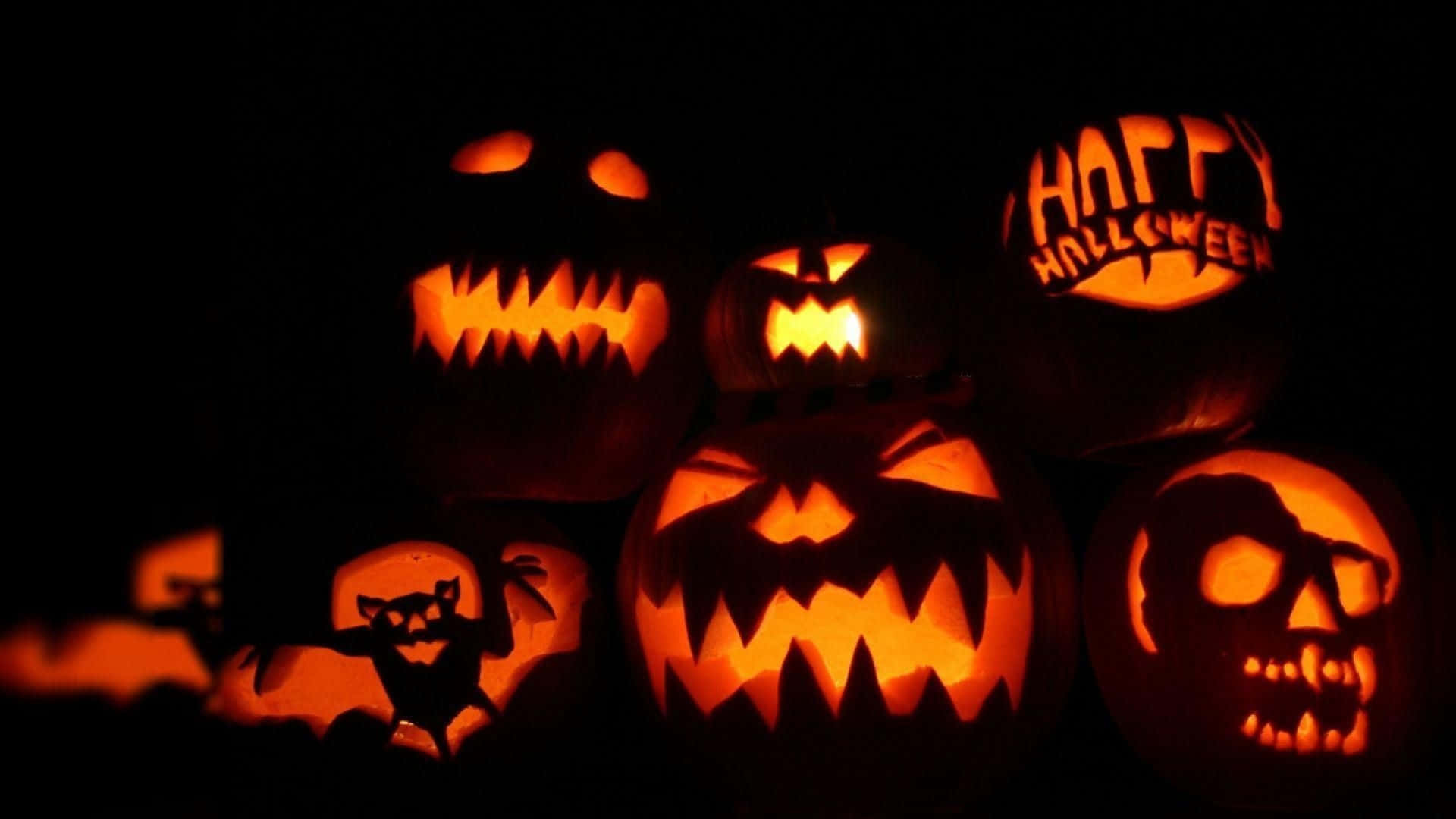 Funny Halloween 桌布 壁紙 — 發光的傑克南瓜燈，帶有兇惡的雕刻面孔和「happy halloween」文字，照亮了黑暗的背景。