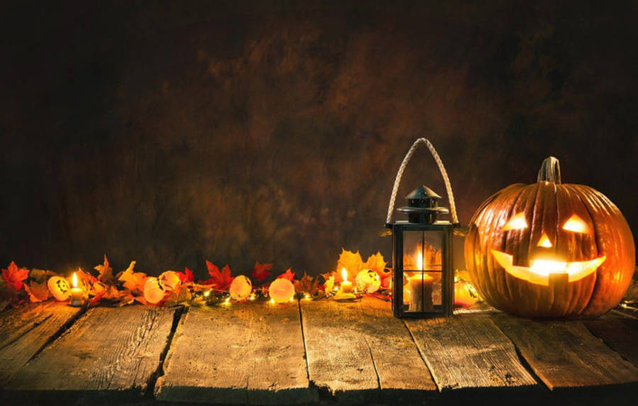 Fall 桌布 壁紙 — 發光的傑克南瓜燈和燈籠將溫暖的光線投射在鄉村木桌上的秋葉和蠟燭上。