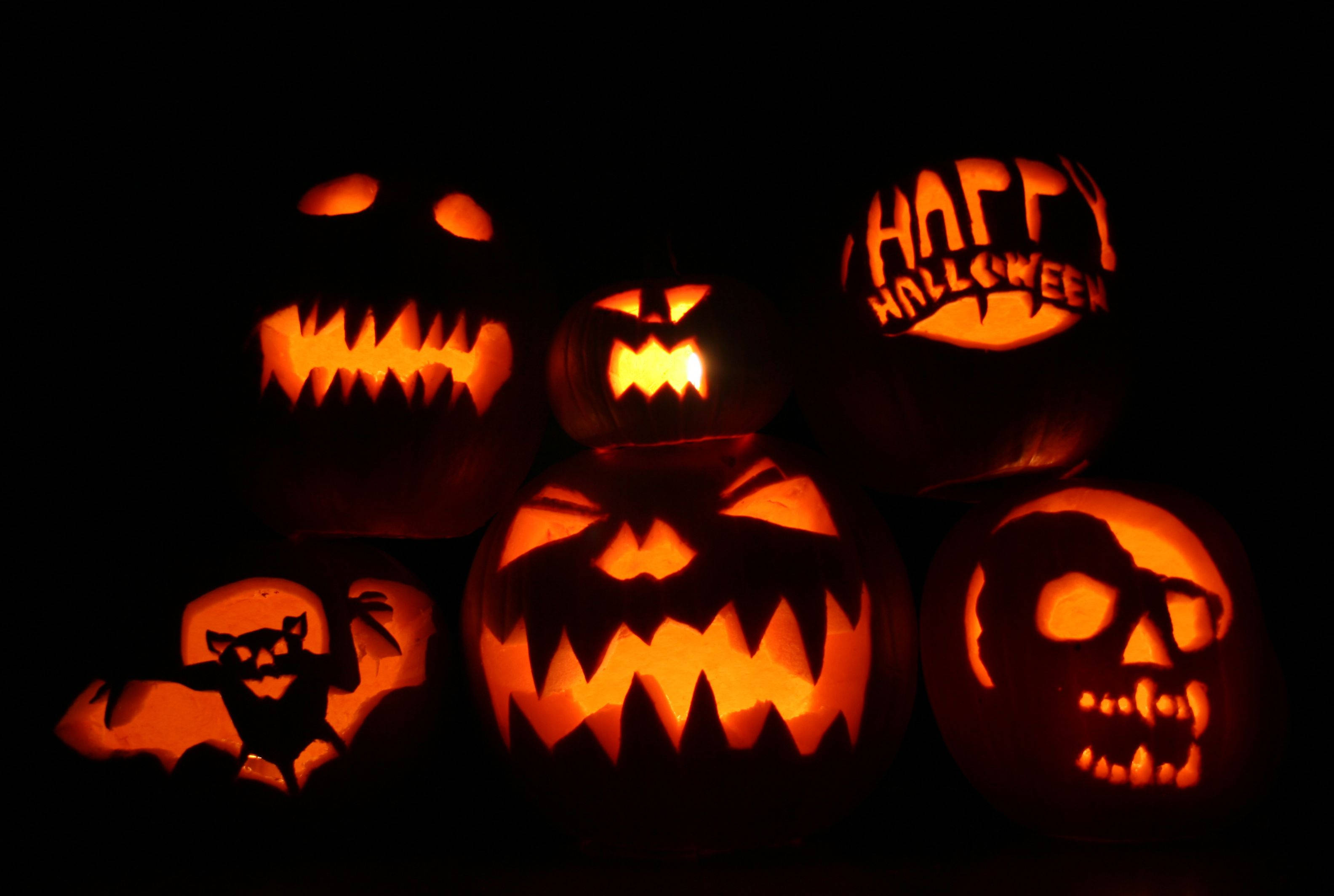 Dark Halloween 桌布 壁紙 — 發光的傑克南瓜燈帶有威脅性的面孔和「Happy Halloween」文字，照亮了黑暗的背景。