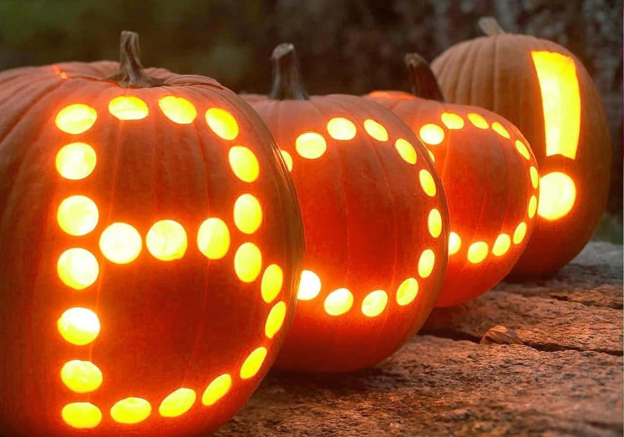 Rock 桌布 壁紙 — 發光的南瓜雕刻著發光的點，拼出「BOO」和驚嘆號，放在黃昏時分的石面上。