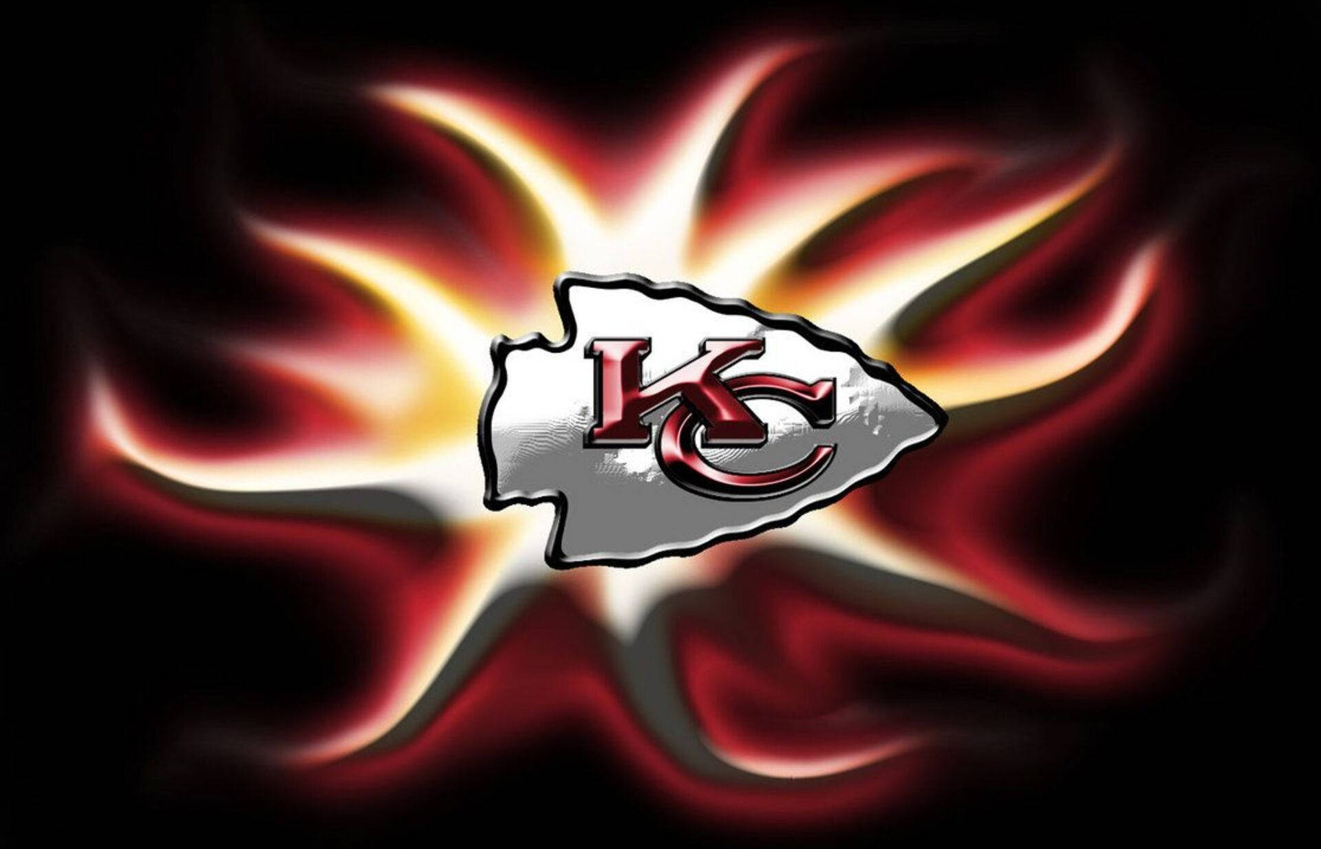 Kansas City Chiefs Cool 桌布 壁紙 — 發光的堪薩斯城酋長標誌在黑暗背景下散發出火紅和金色的能量。